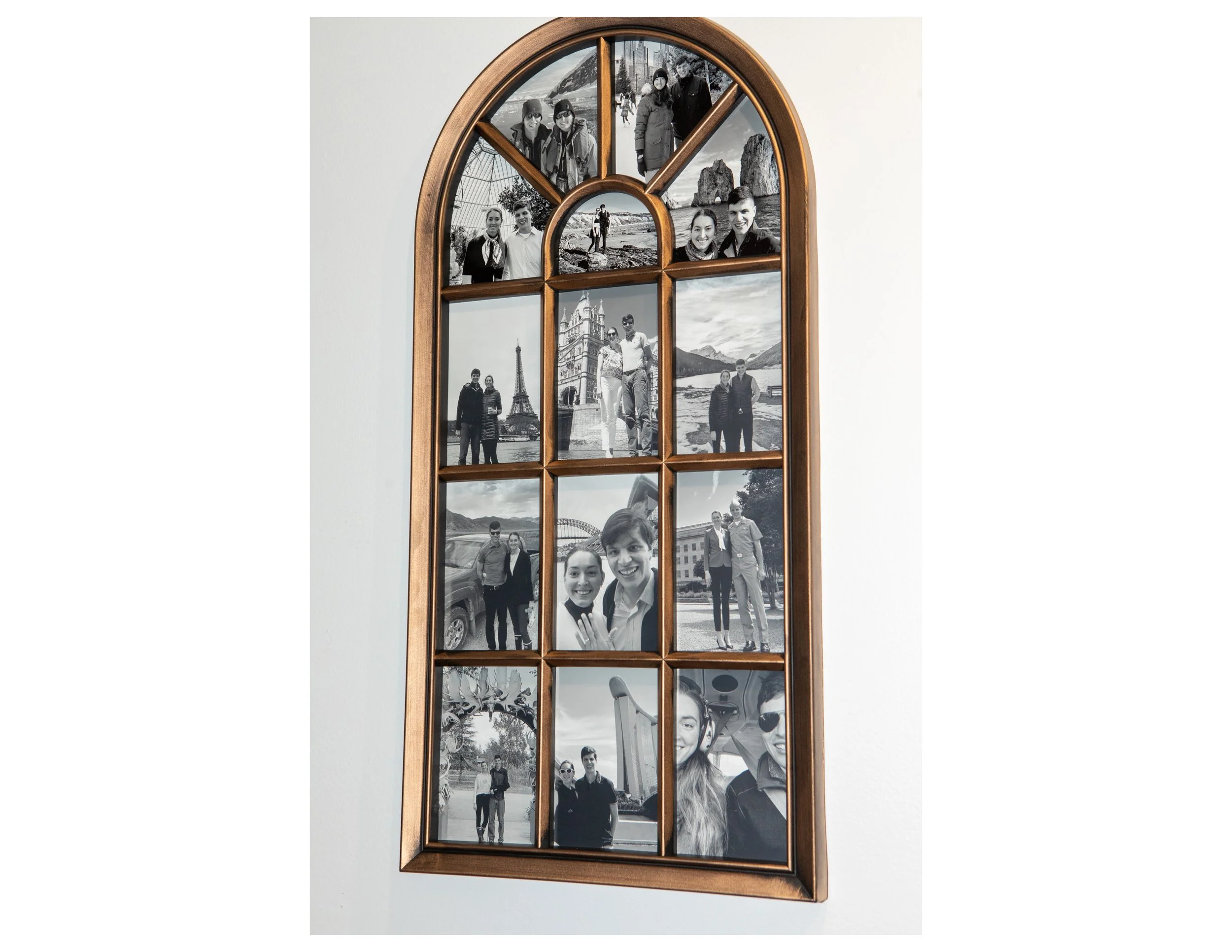 A wooden framed wall mirror with multiple partitions displaying various black and white photographs of people and scenic locations.