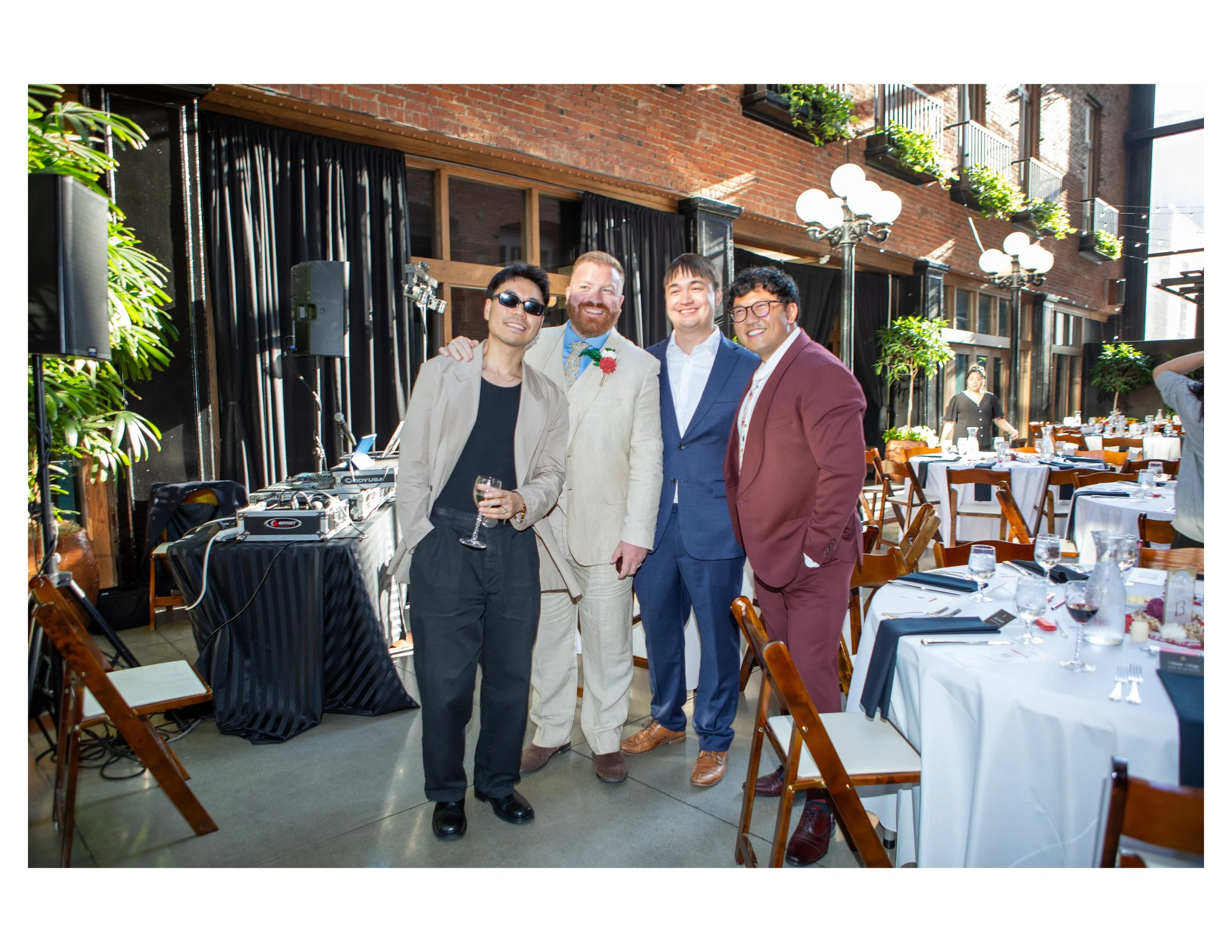 Four men dressed in formal and semi-formal attire standing together at an indoor event, smiling and posing for the camera.