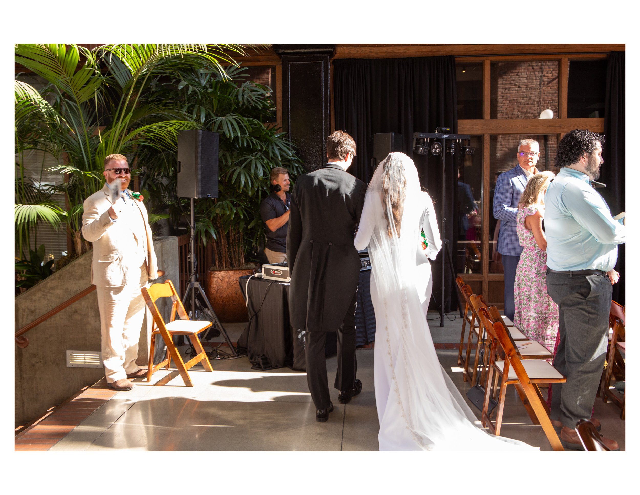 People gathered indoors for a wedding ceremony, with the bride and groom facing each other.