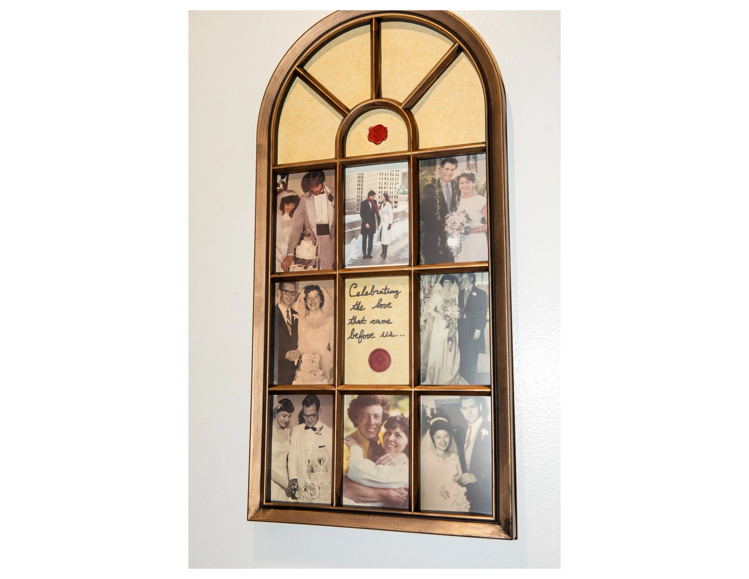 A wall-mounted wooden photo frame collage with several vintage wedding and family photographs and a handwritten note that says, 'Celebrating the love that came before us...' with a red wax seal.