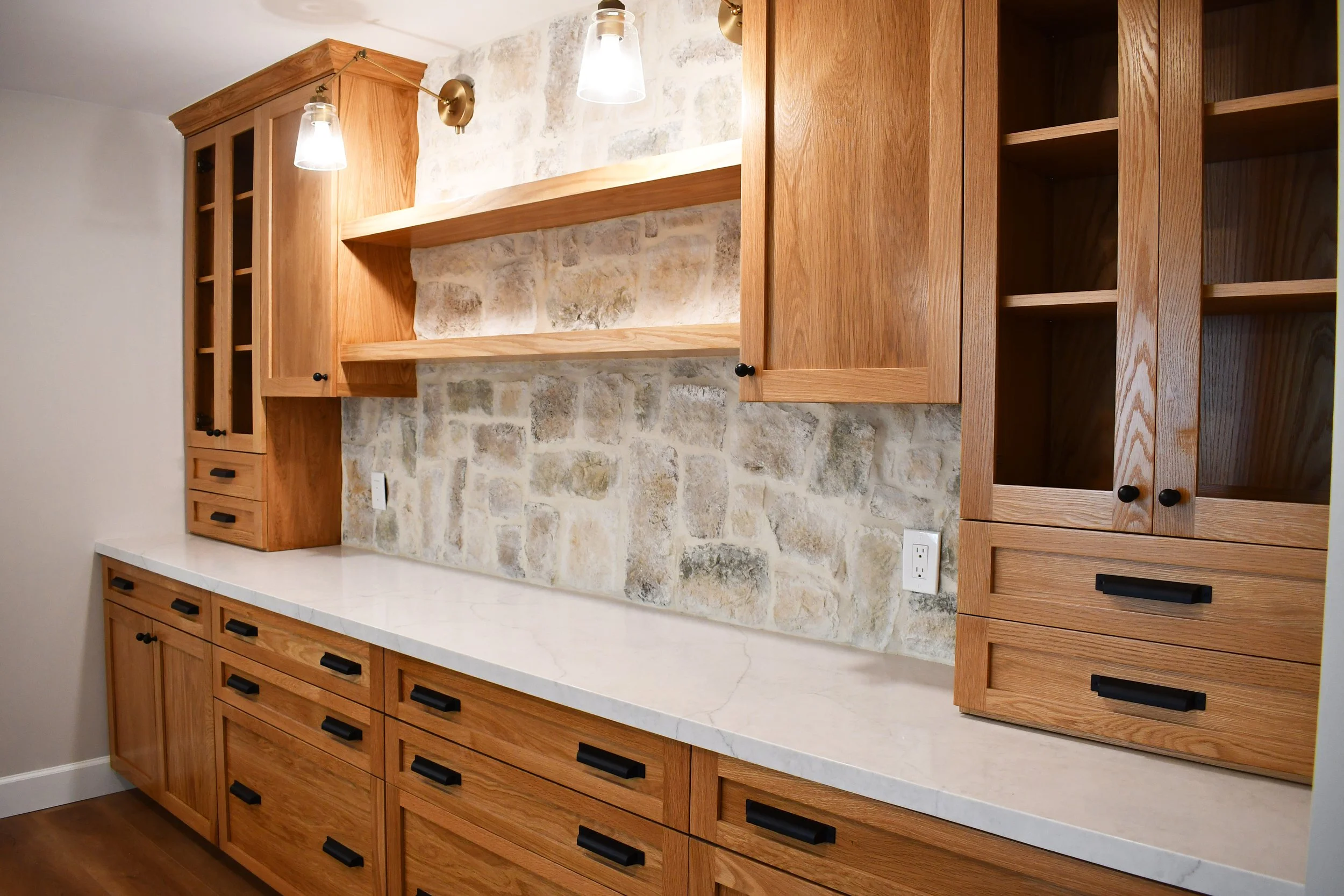 Modern kitchen with wooden cabinets, stone backsplash, and marble countertop.
