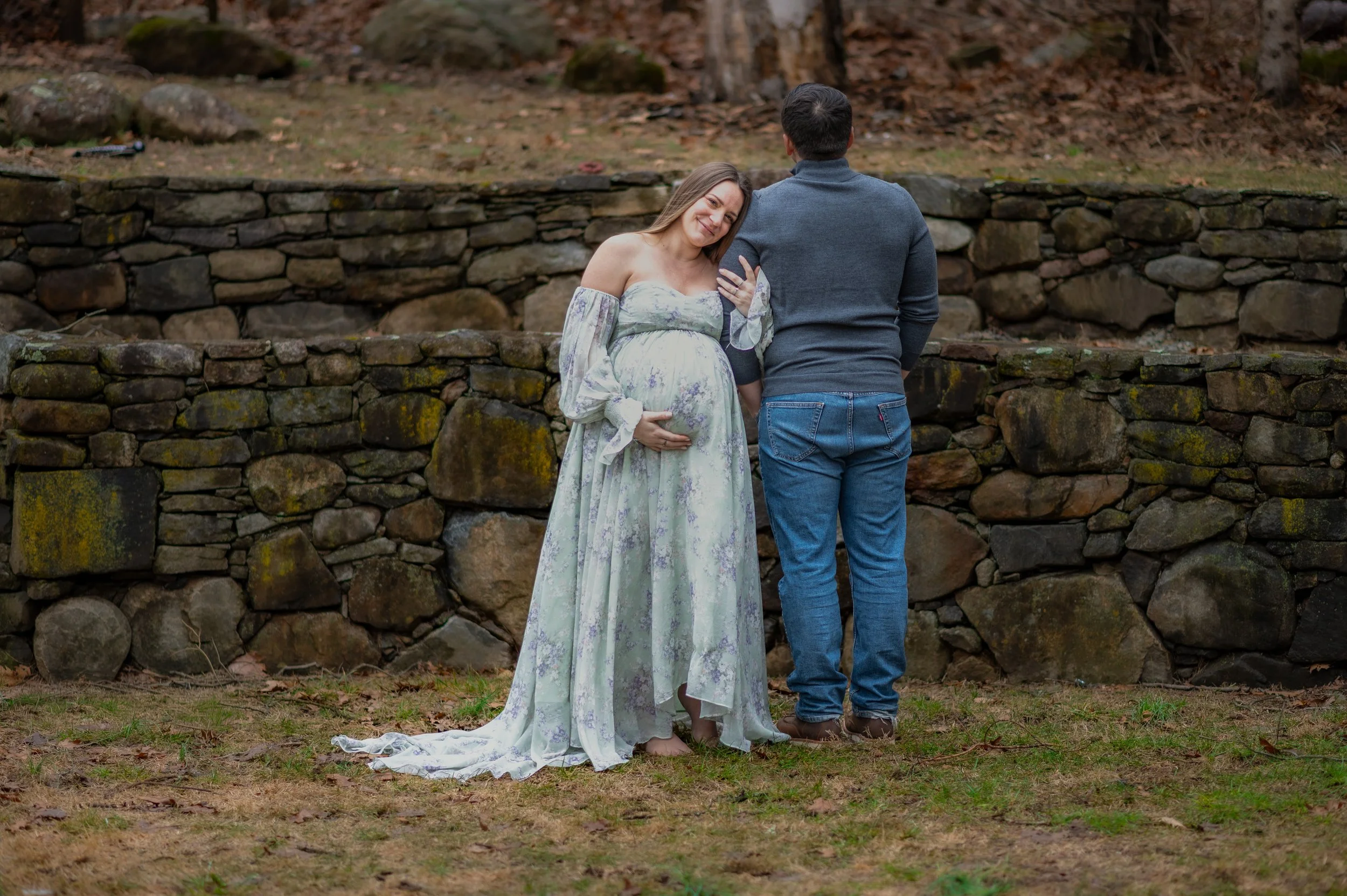 A pregnant wife rests her head on her husband's shoulder