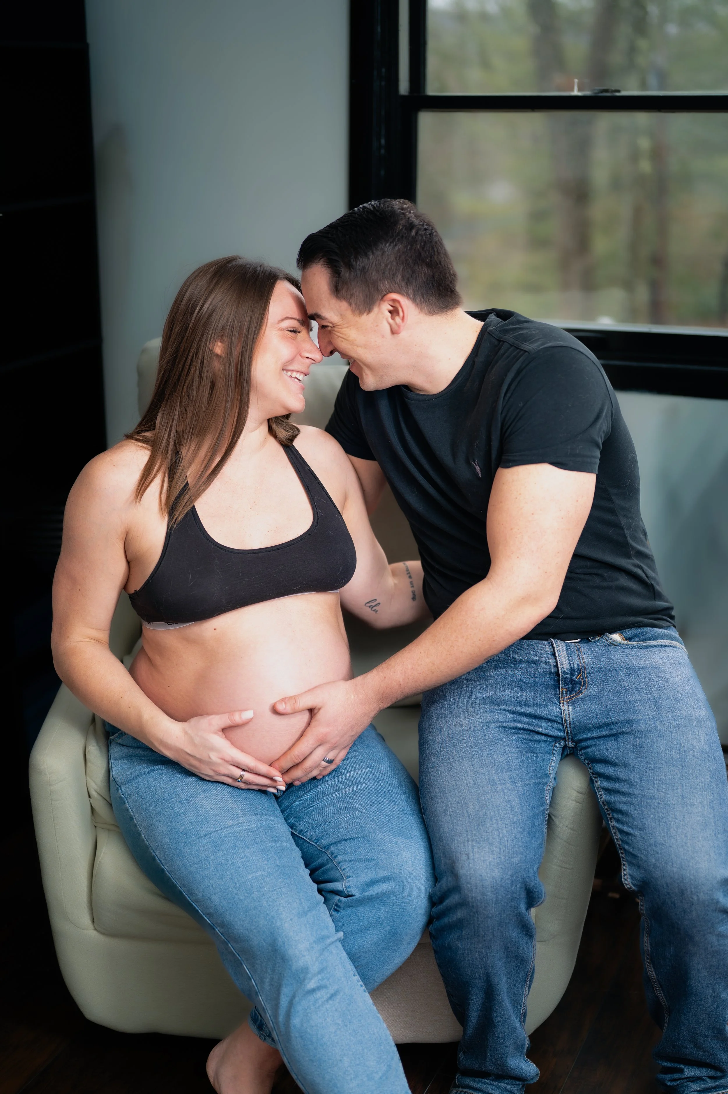 An in-home maternity photo session, husband and wife nuzzling heads together