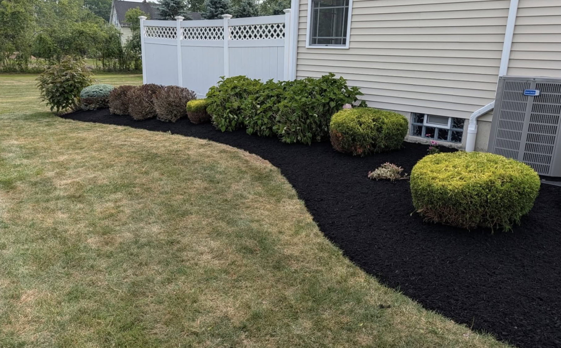 Freshly mulched landscape bed with trimmed shrubs at a residential property in Grand Island, NY by Kielty Landscaping
