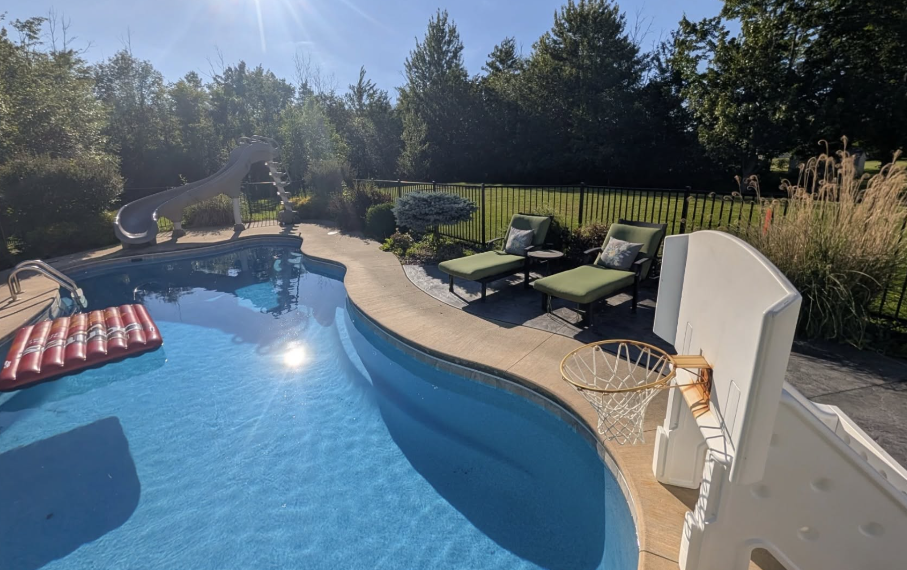 Professional landscape maintenance around a backyard swimming pool with trimmed shrubs, clean mulch beds, and healthy landscaping.