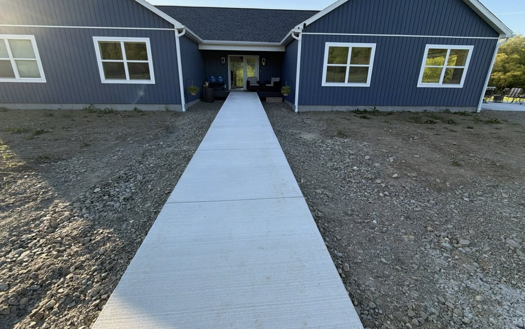 Before photo of a new landscape installation with unfinished front yard before planting, seeding, and granite cobblestone edging by Kielty Landscaping.