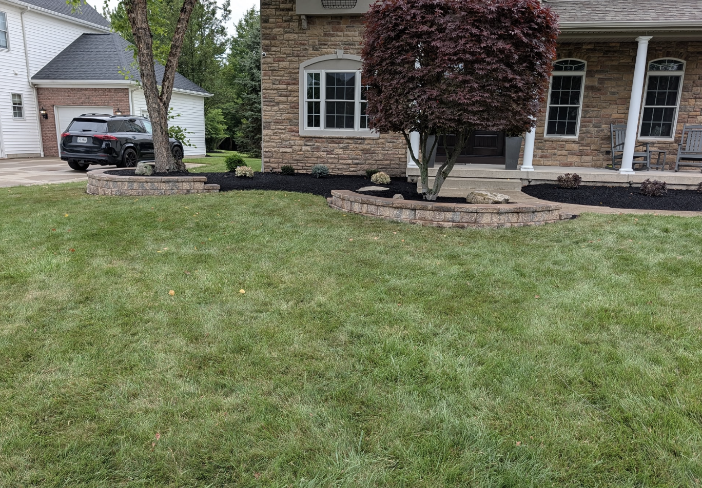 Front yard landscaping renovation with new plants, mulch beds, retaining walls, and sod in Grand Island, NY