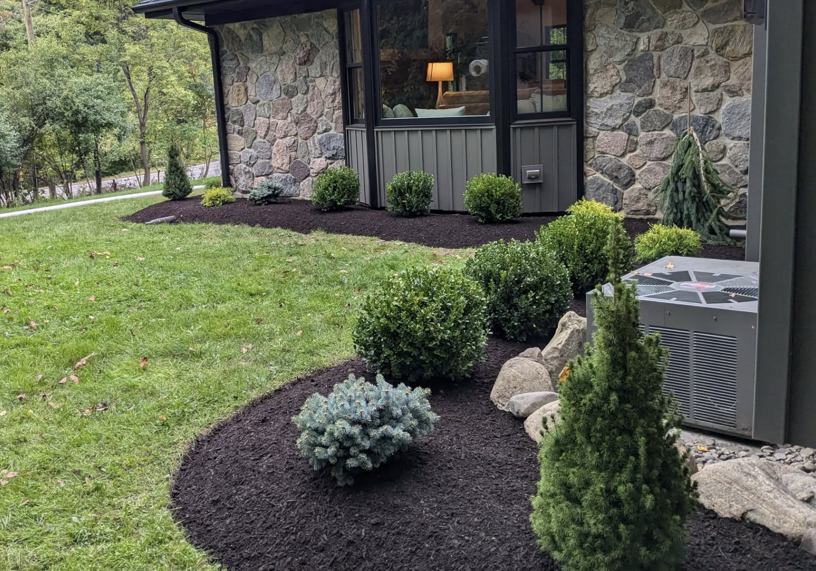 Landscape maintenance with manicured shrubs, stone edging, and clean garden beds in Orchard Park, New York.