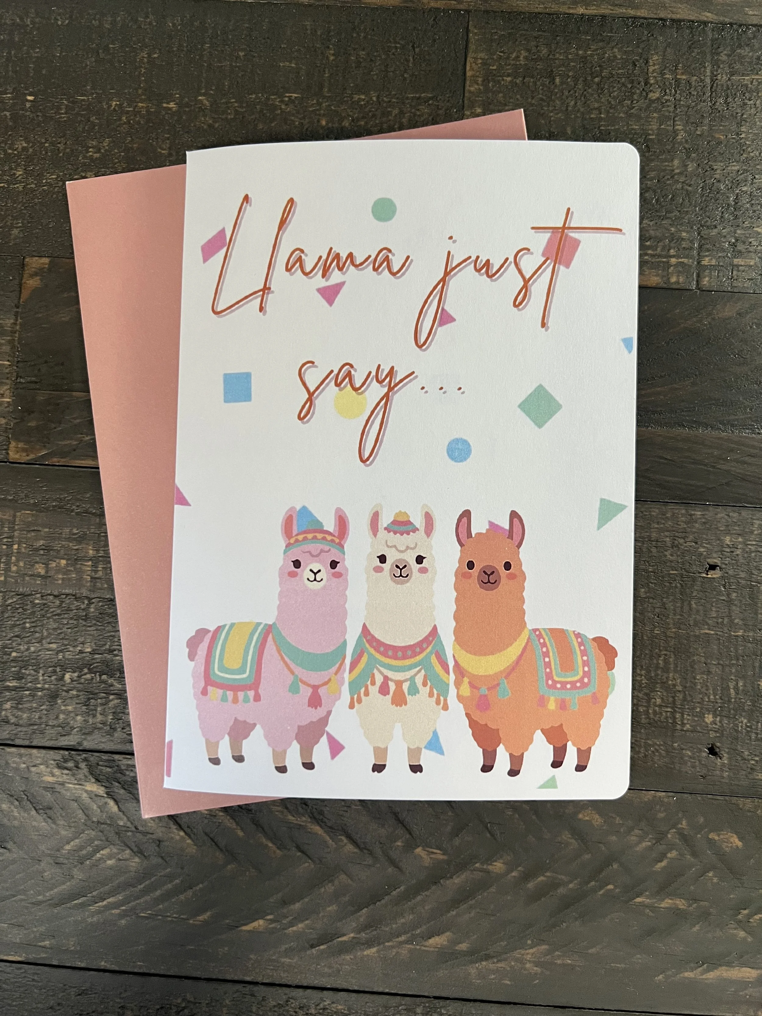 Colorful llama birthday card with confetti and festive llama illustrations on wood background