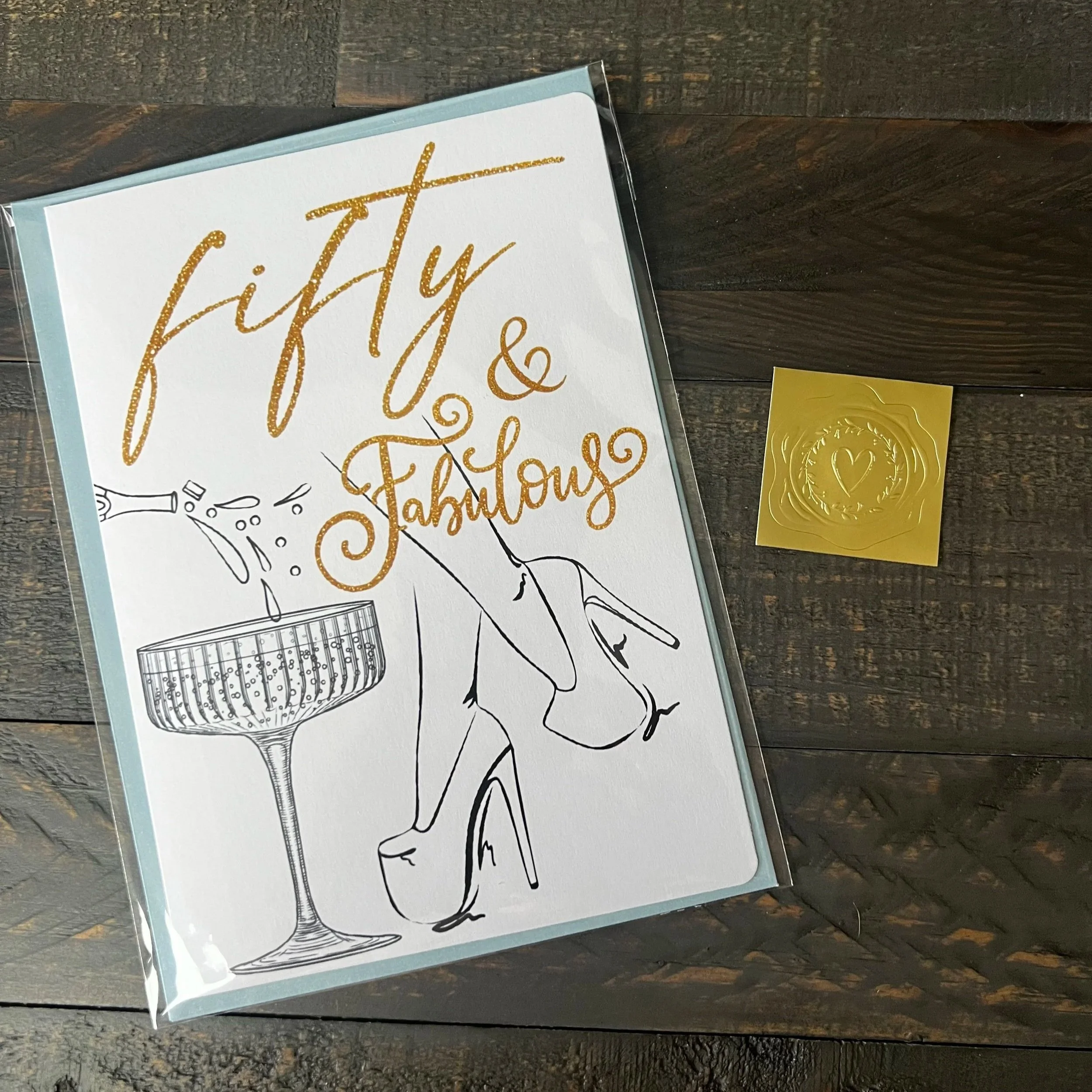 Fifty & Fabulous birthday greeting card with coordinating soft blue envelope and gold wax seal style sticker.
