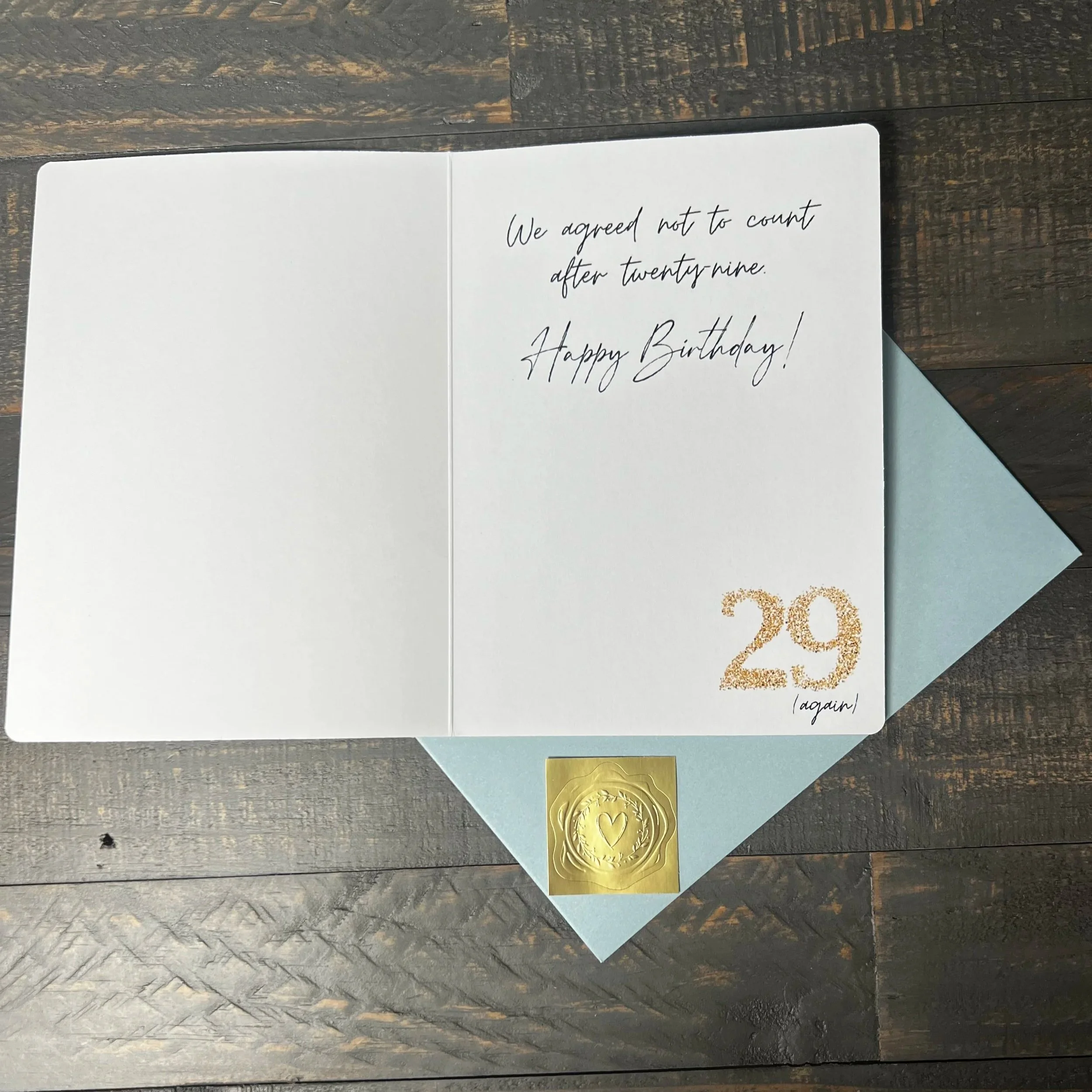 Open Twenty-Nine Again greeting card with coordinating envelope and gold wax seal style sticker.