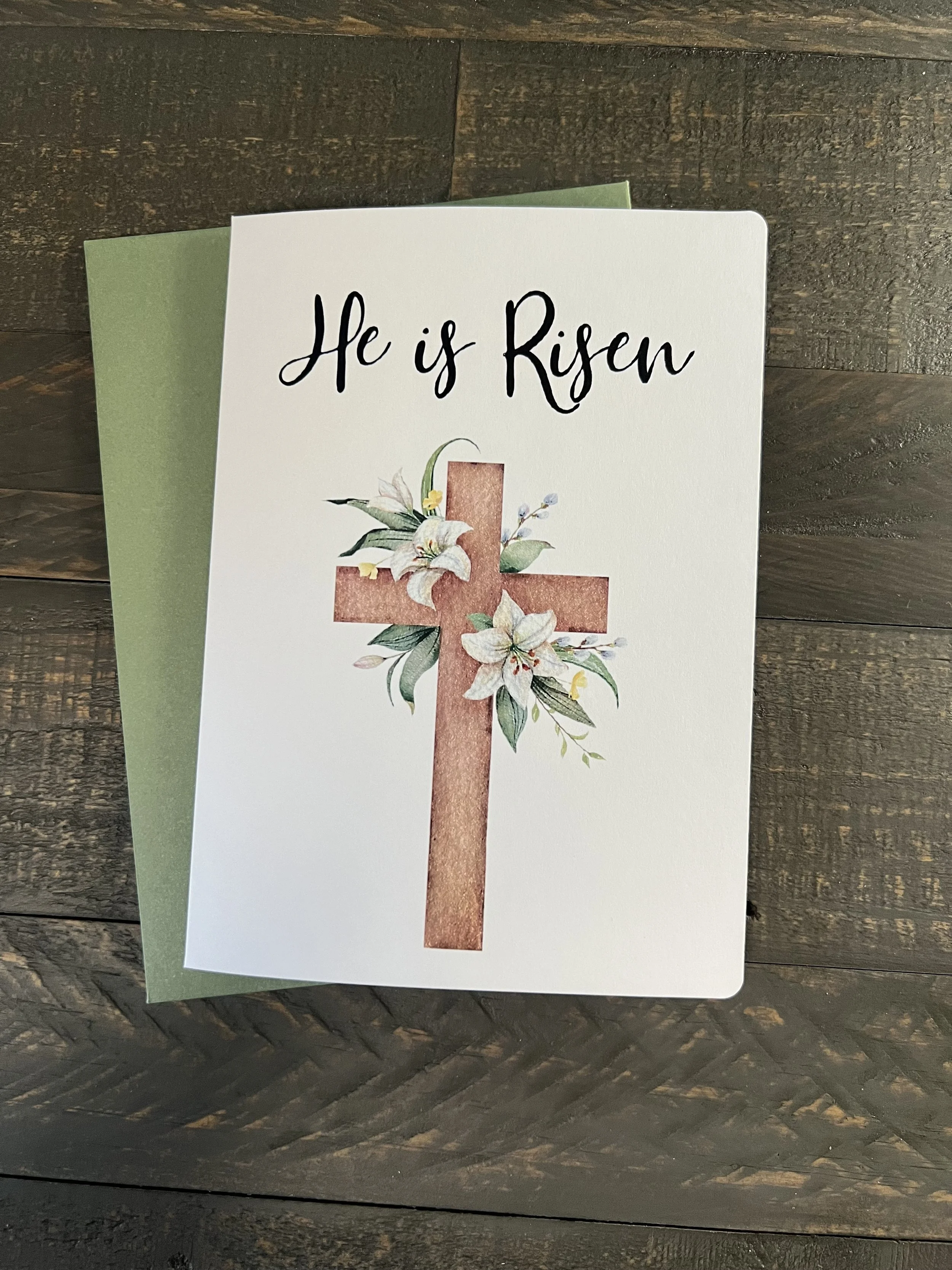 “He is Risen” Easter card with watercolor floral cross design on textured neutral background