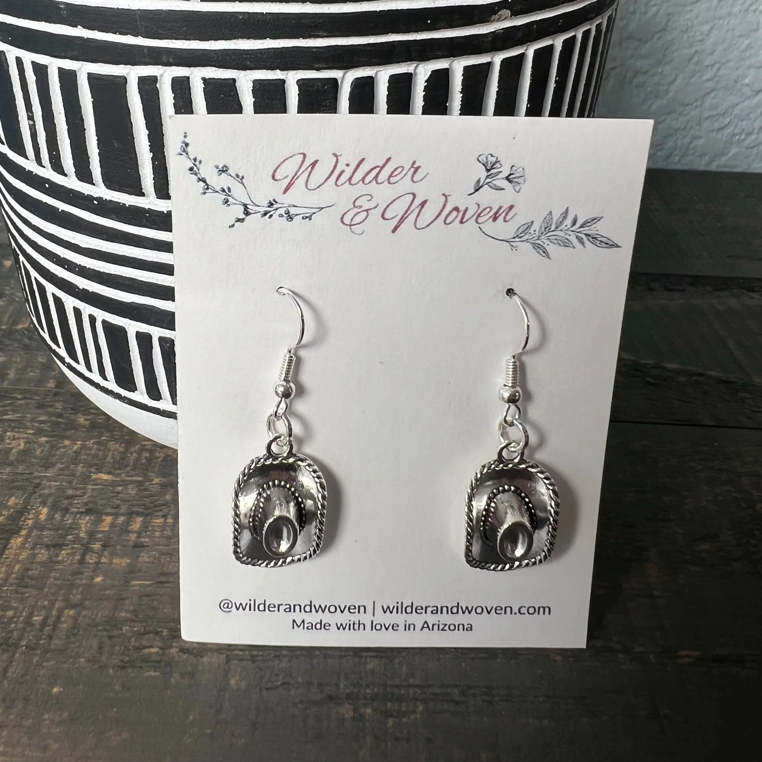 Silver western hat charm earrings with vintage detailing, displayed on a Wilder & Woven branded jewelry card.