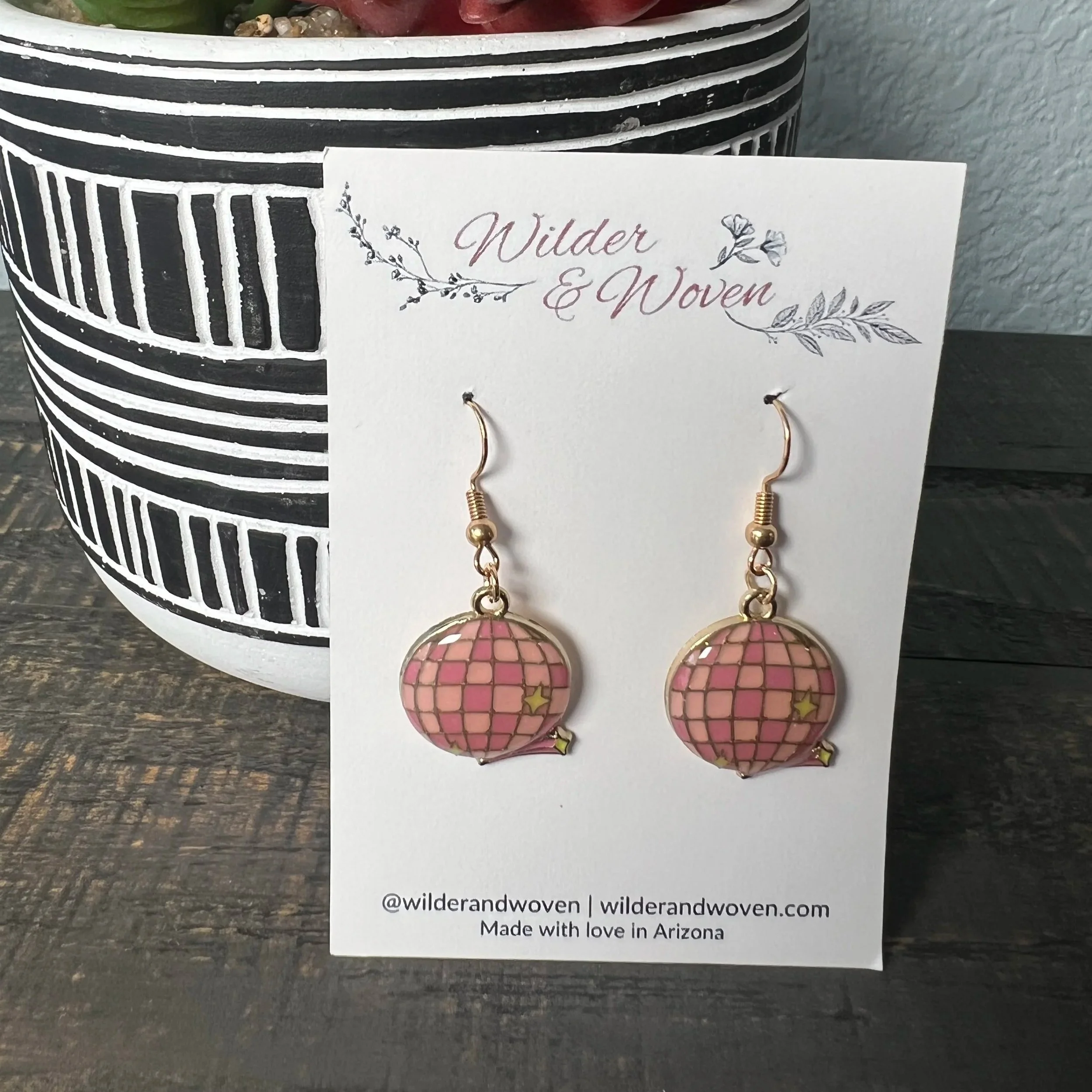 Pink enamel disco ball charm earrings with gold trim, displayed on a Wilder & Woven branded jewelry card.