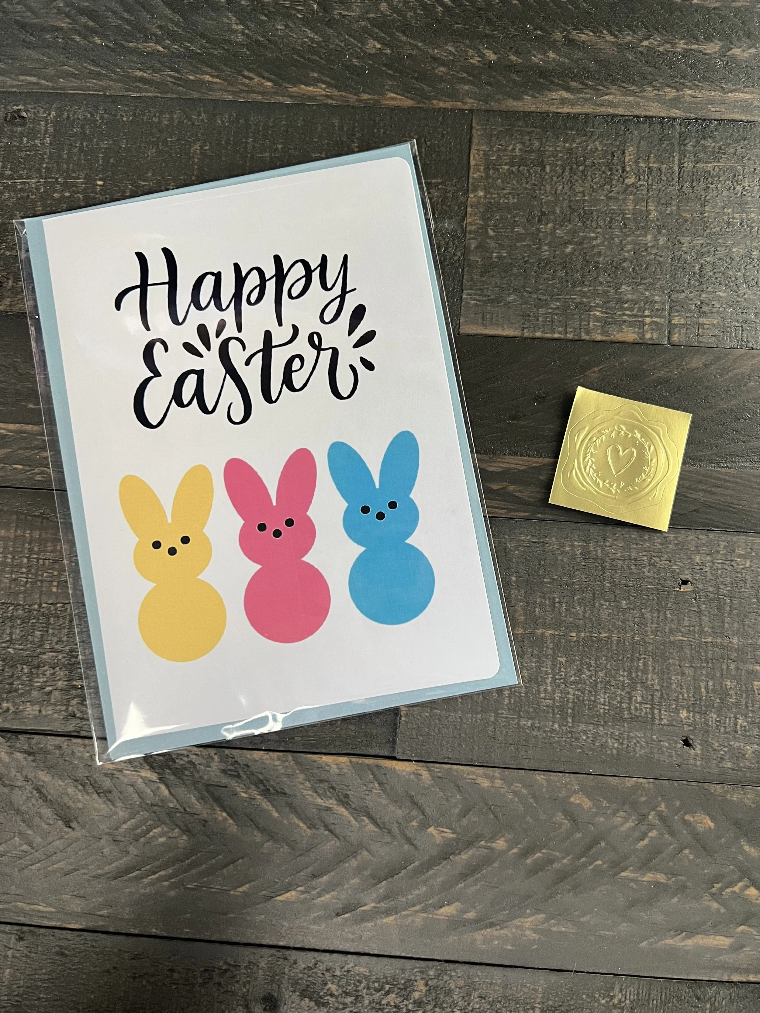 Colorful bunny Easter card with coordinating envelope and gold wax seal sticker styled on wood surface