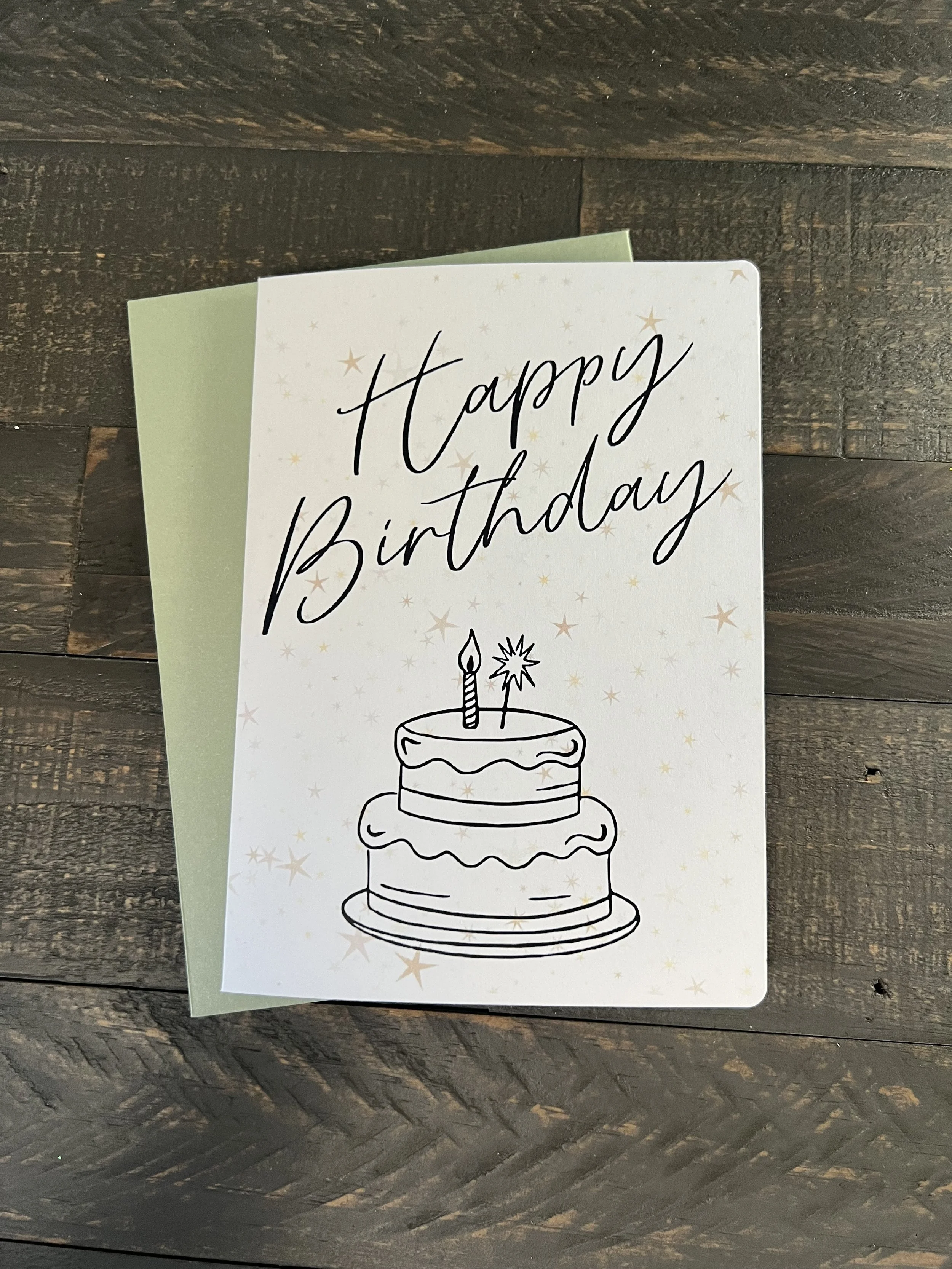 Happy birthday card with hand-drawn cake illustration and minimal speckled design on wood background