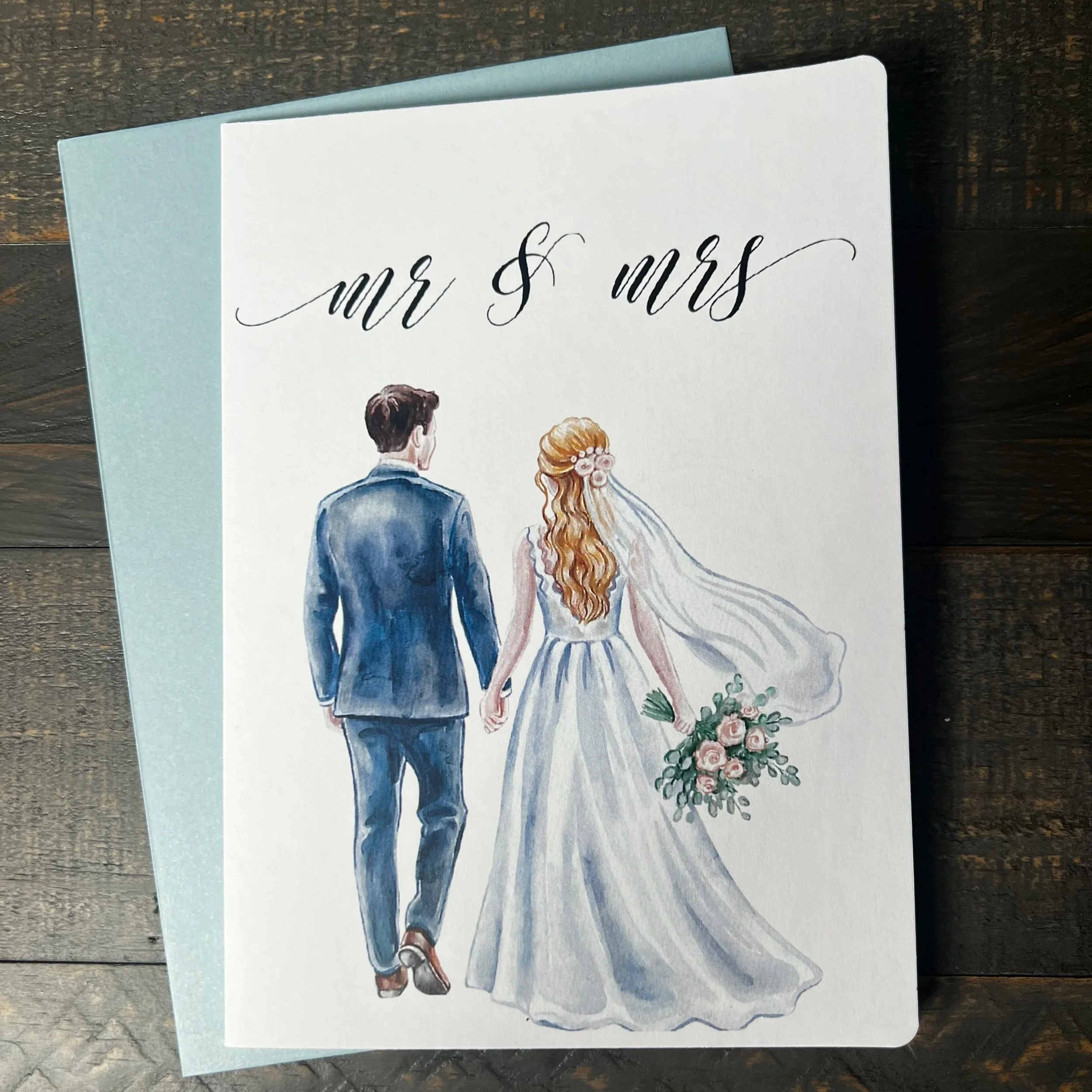 Front of Mr. & Mrs. wedding greeting card featuring a blonde bride with coordinating soft blue envelope.