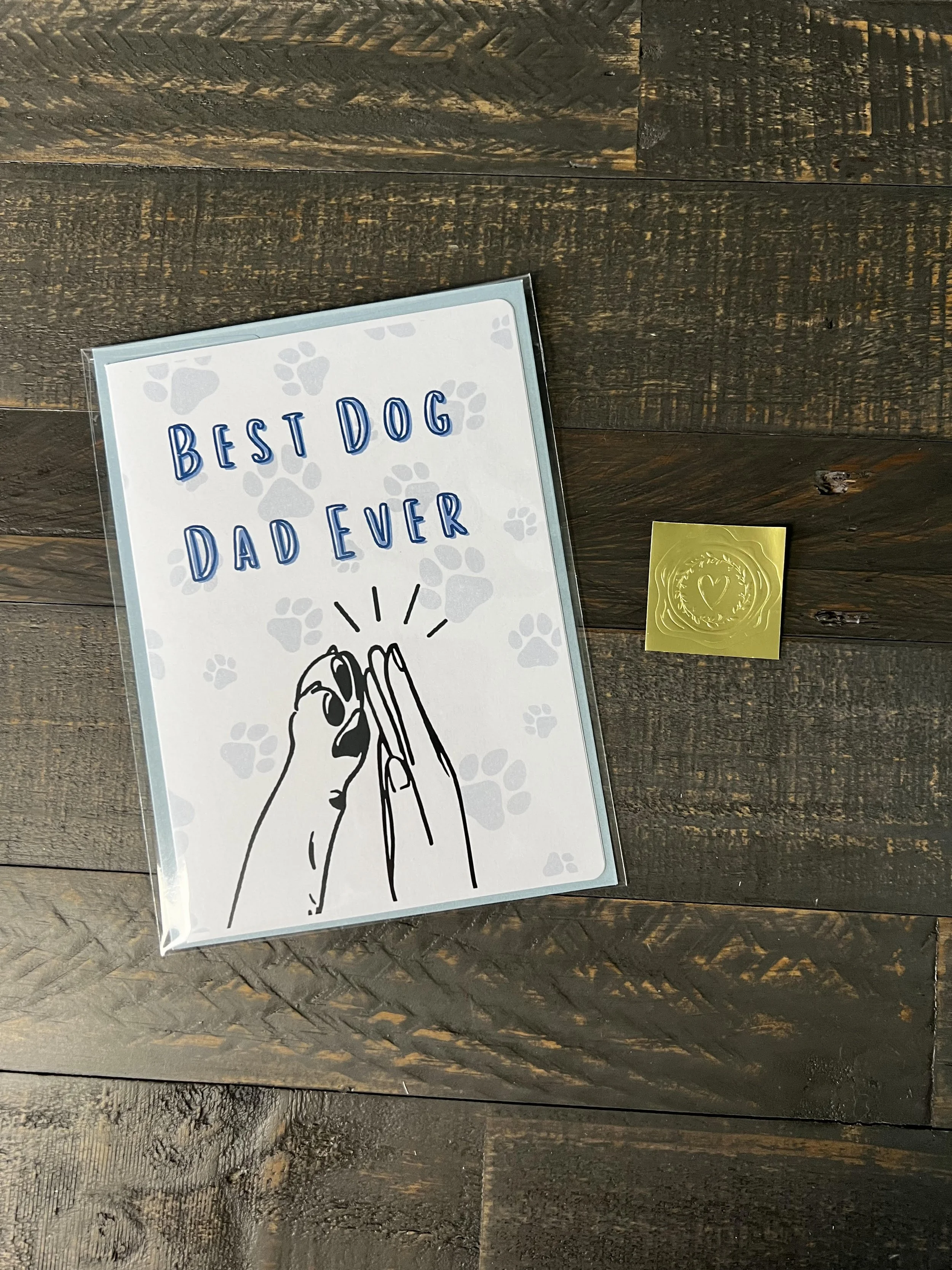 Dog dad Father’s Day card styled with light blue envelope and gold wax seal sticker on wood background