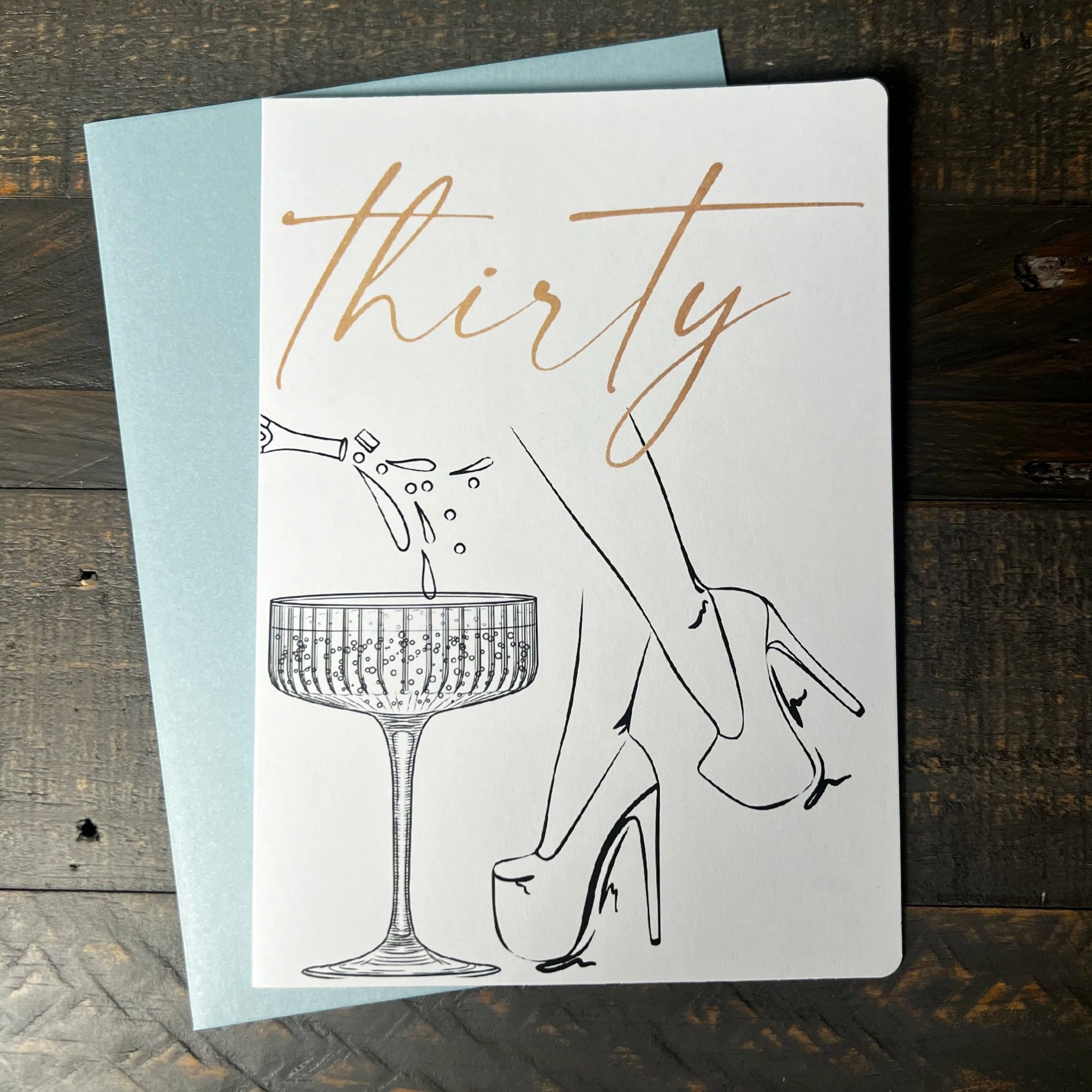 Thirty birthday greeting card featuring champagne glass and elegant heels illustration.