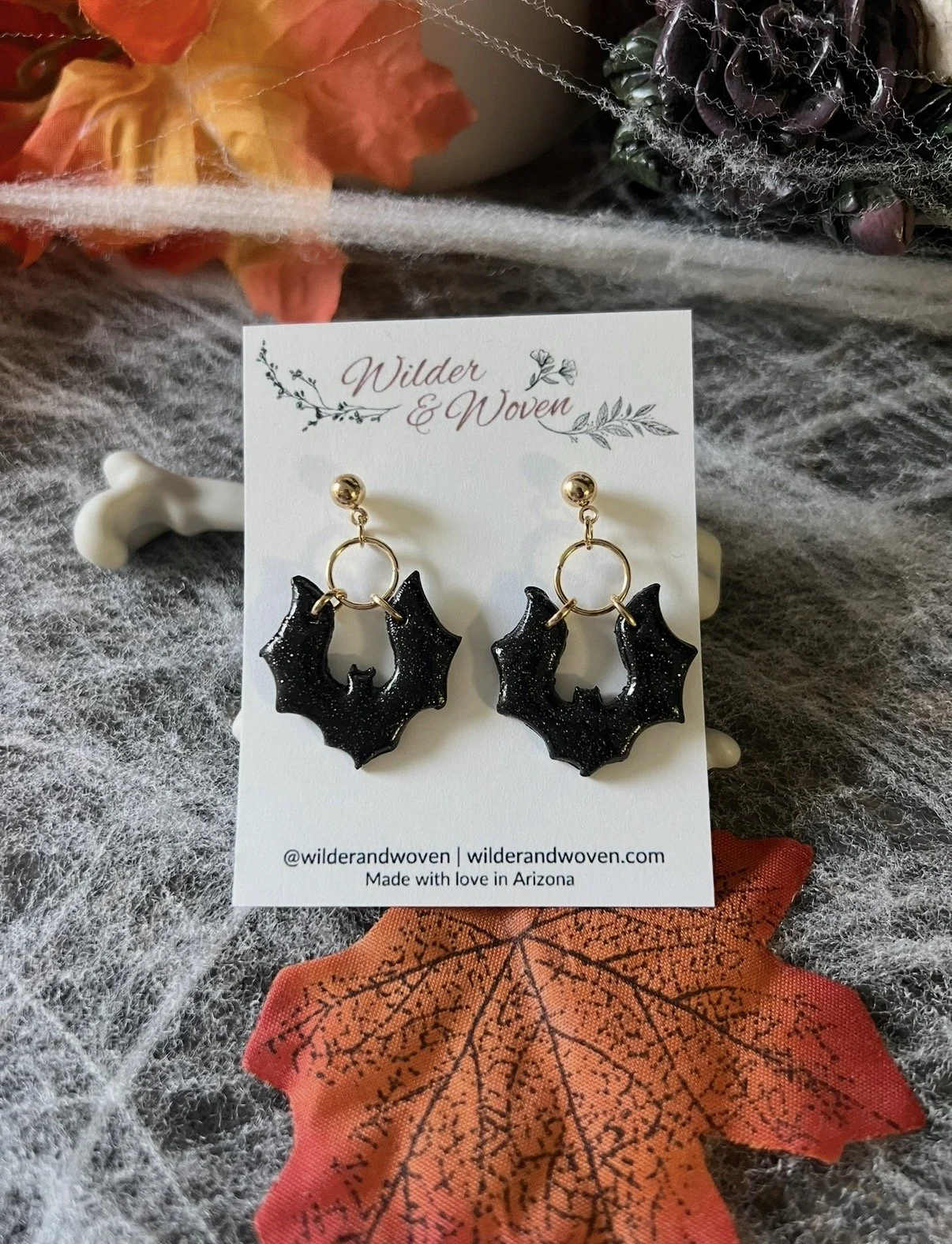 Midnight Bat Dangle handmade polymer clay earrings featuring shimmering black bats, gold hoops, and gold ball posts by Wilder & Woven.