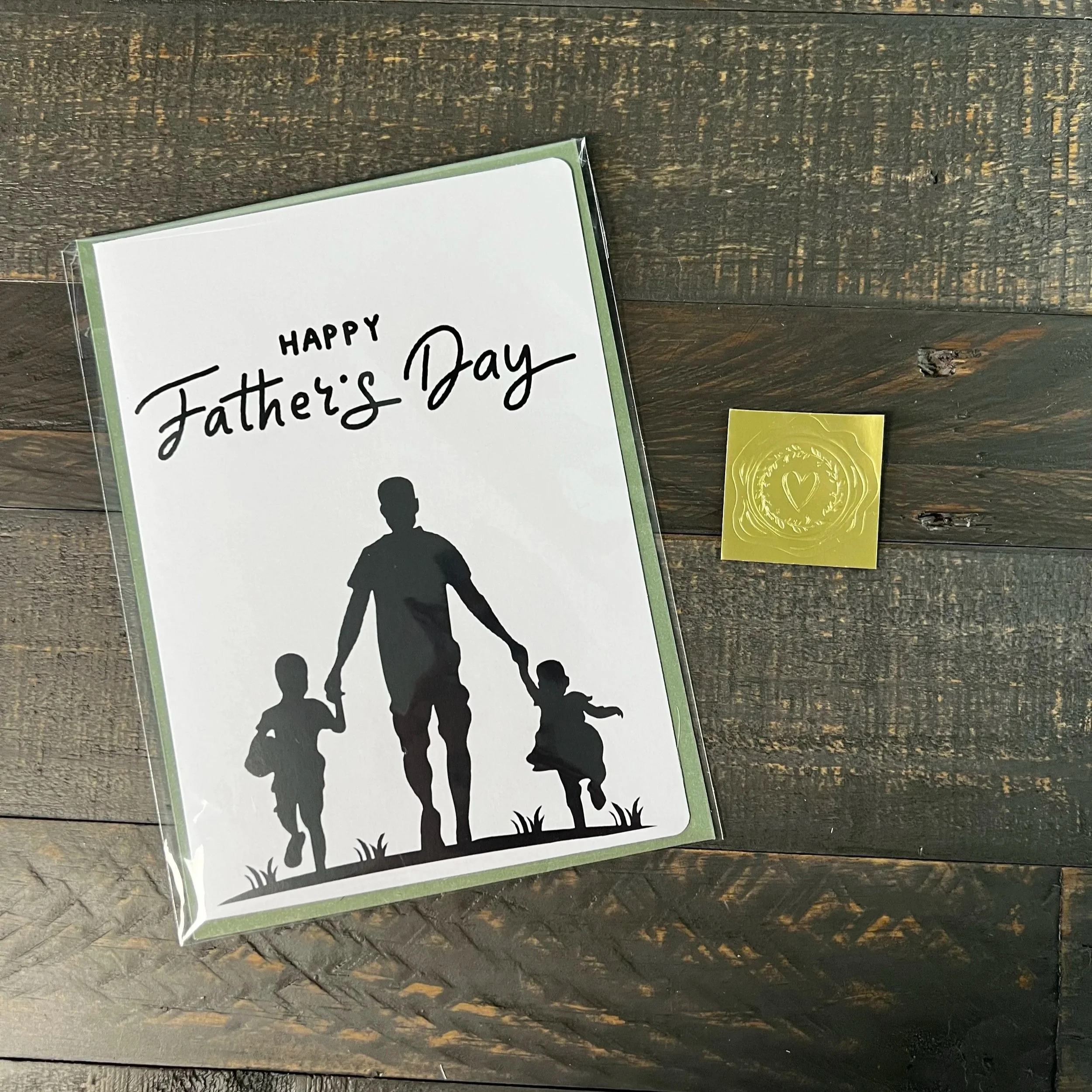Father’s Day card styled with sage green envelope and gold wax seal sticker on wood surface