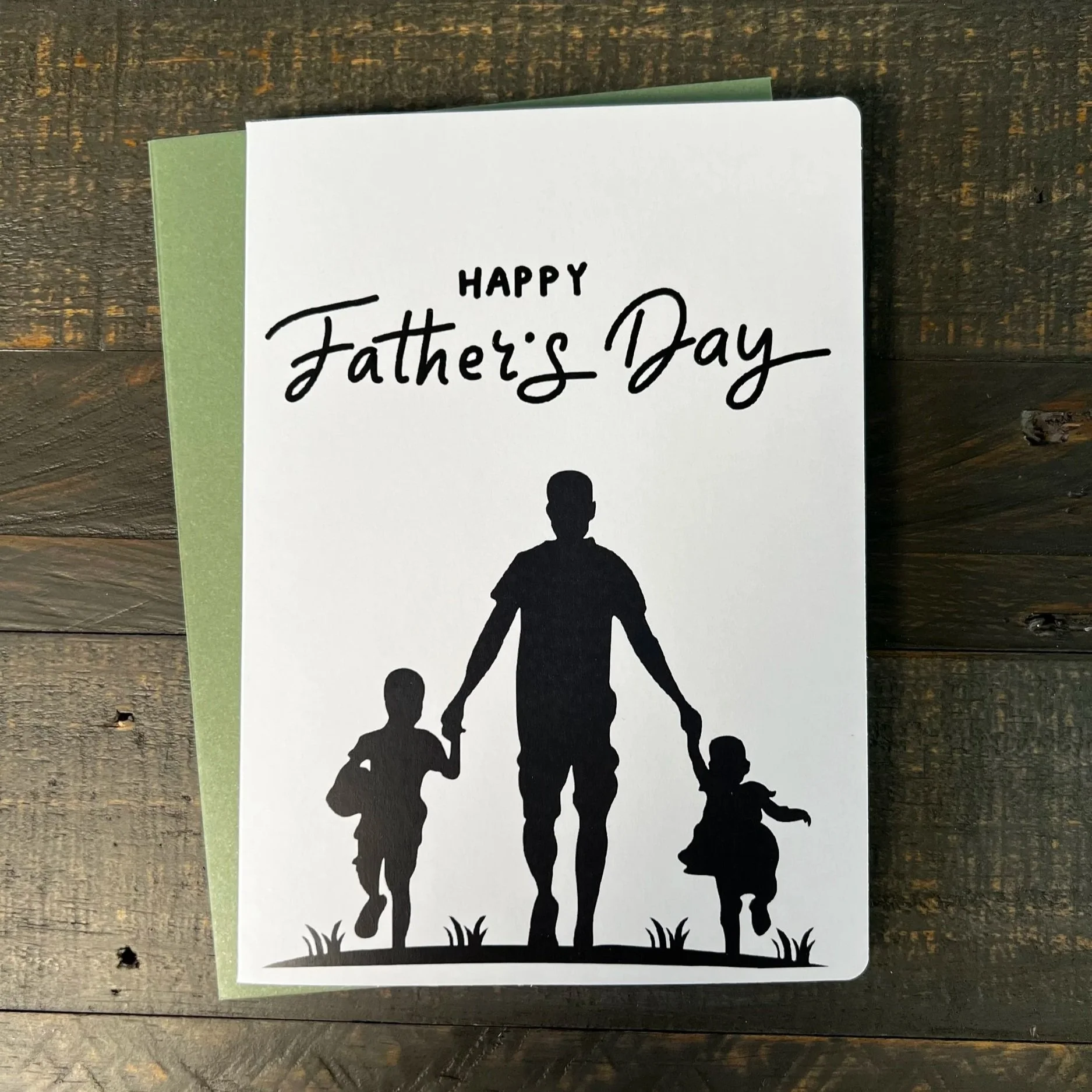 Sentimental Father’s Day card with silhouette family design on wood background