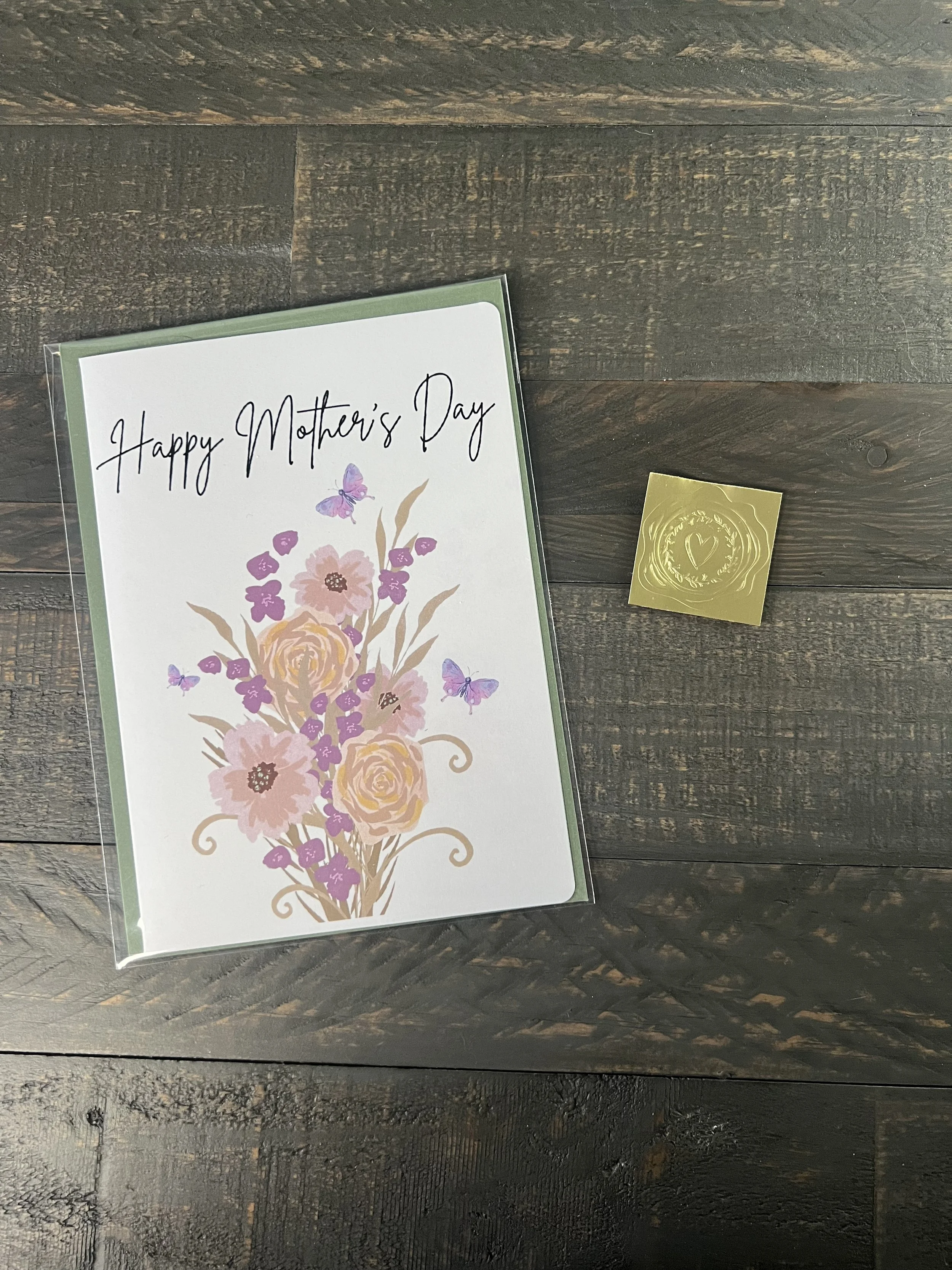 Packaged Mother’s Day card with wildflower bouquet design, sage green envelope, and gold wax seal sticker on wood surface