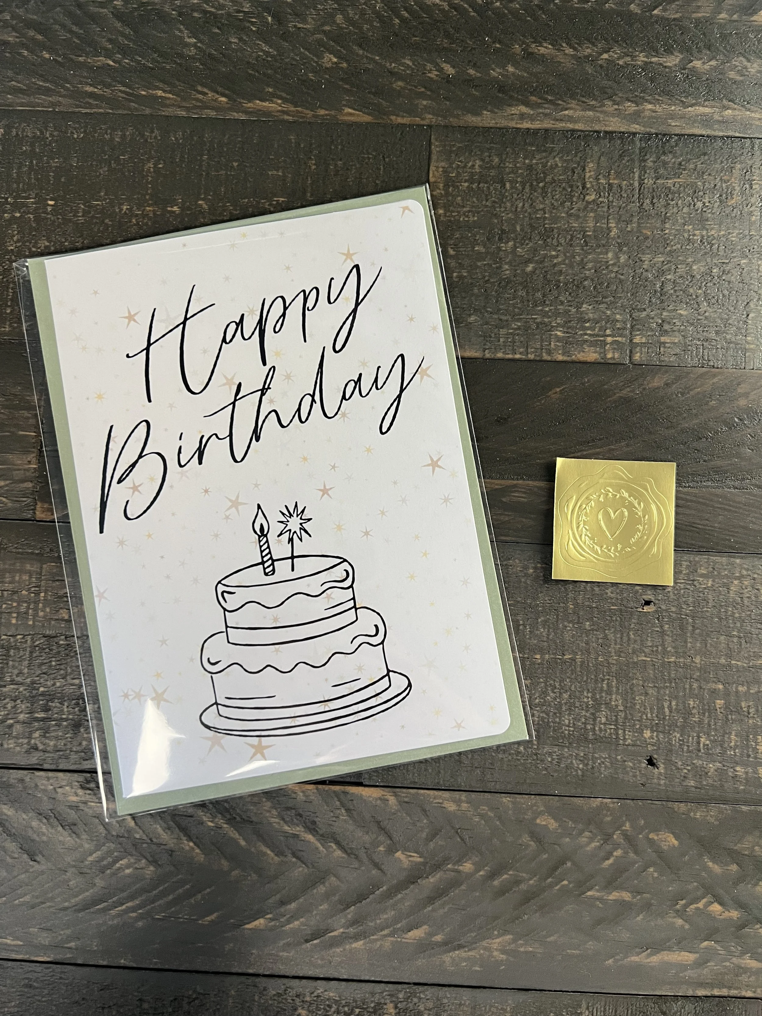Birthday cake card with coordinating envelope and gold wax seal sticker styled on rustic surface