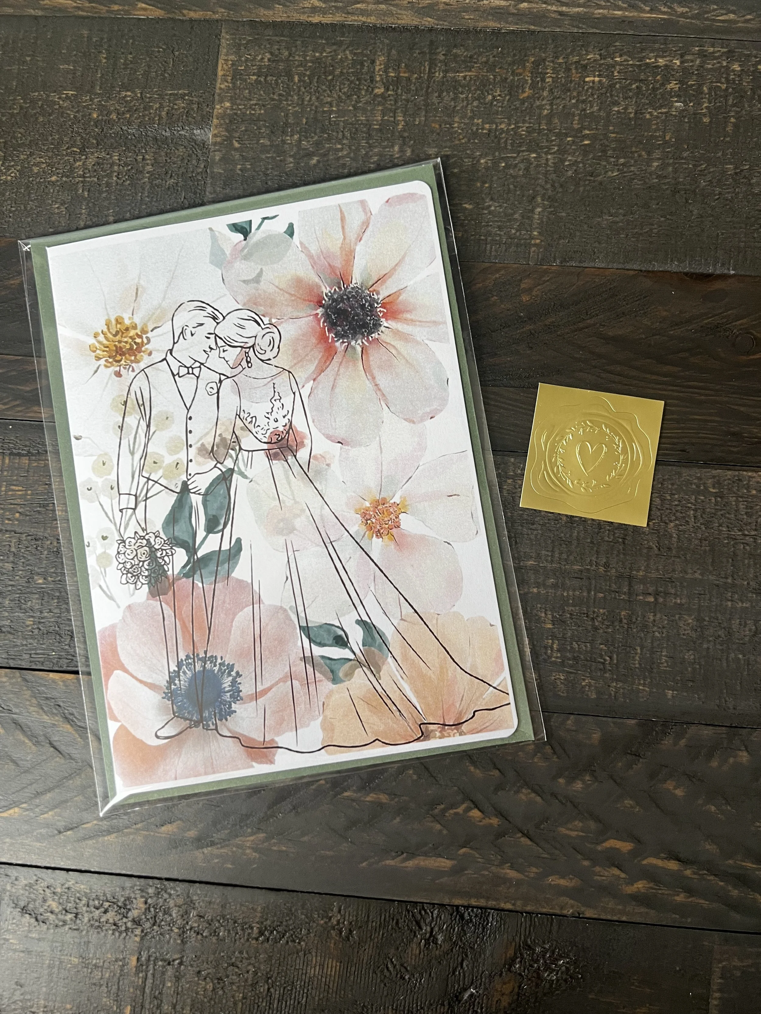 Styled flat lay of Beginning of a Lifetime Wedding Card with coordinating sage green envelope and gold wax seal style sticker.