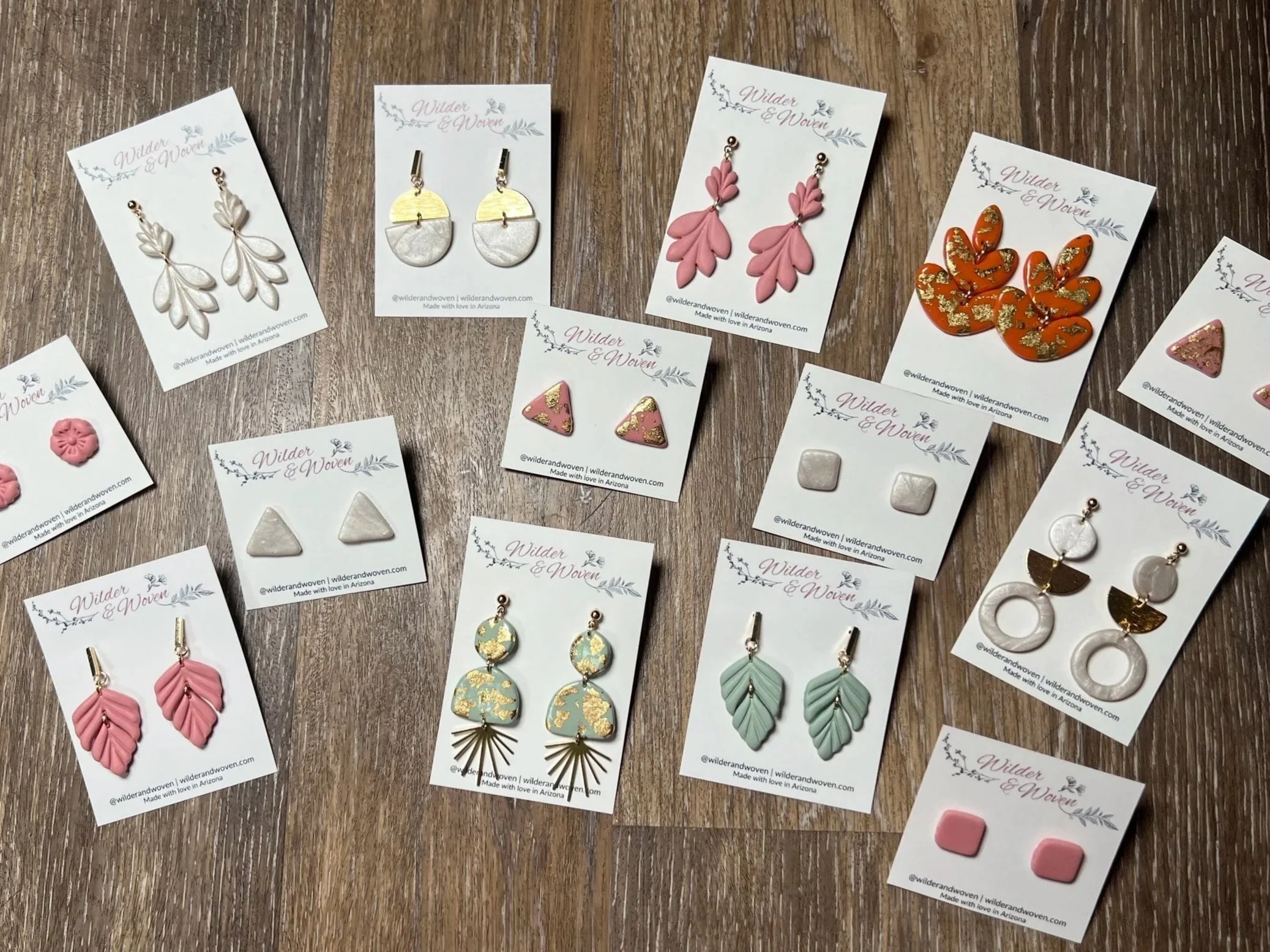 Flat lay of handcrafted polymer clay earrings by Wilder & Woven, featuring everyday statement and neutral designs on a wood background.