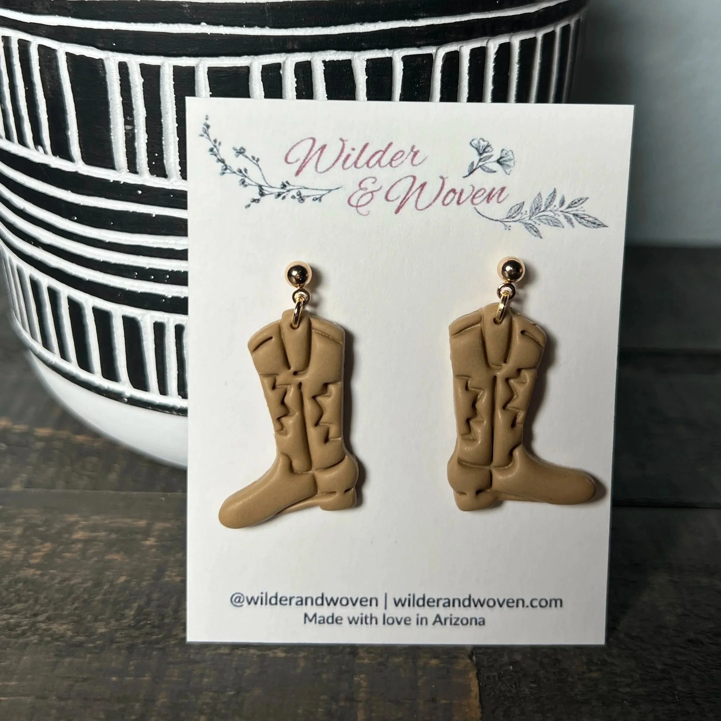 Handcrafted polymer clay cowgirl boot statement earrings in a warm sandy desert tone, displayed on a Wilder & Woven branded jewelry card.