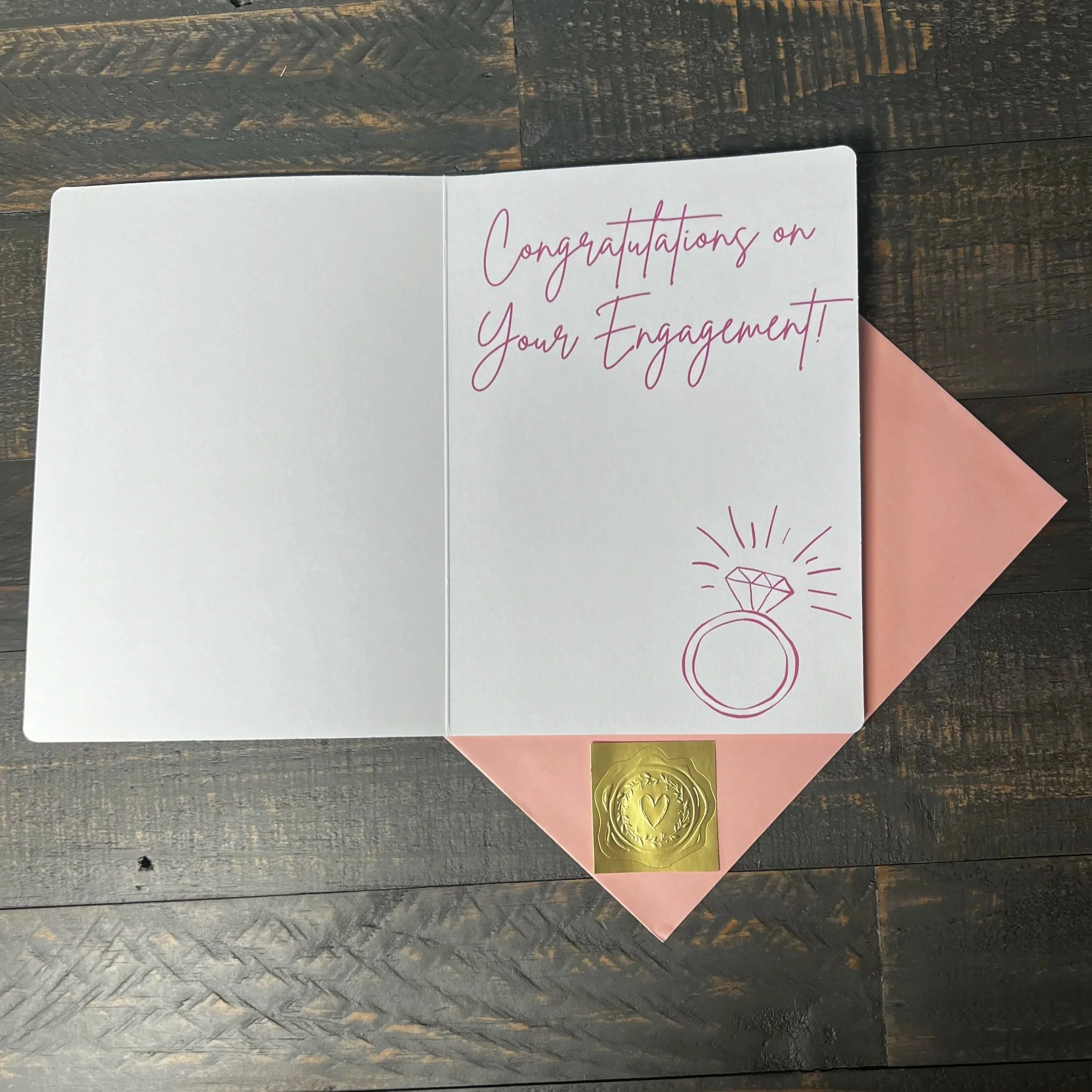 Open She Said Yes! engagement card with coordinating blush pink envelope and gold wax seal style sticker.
