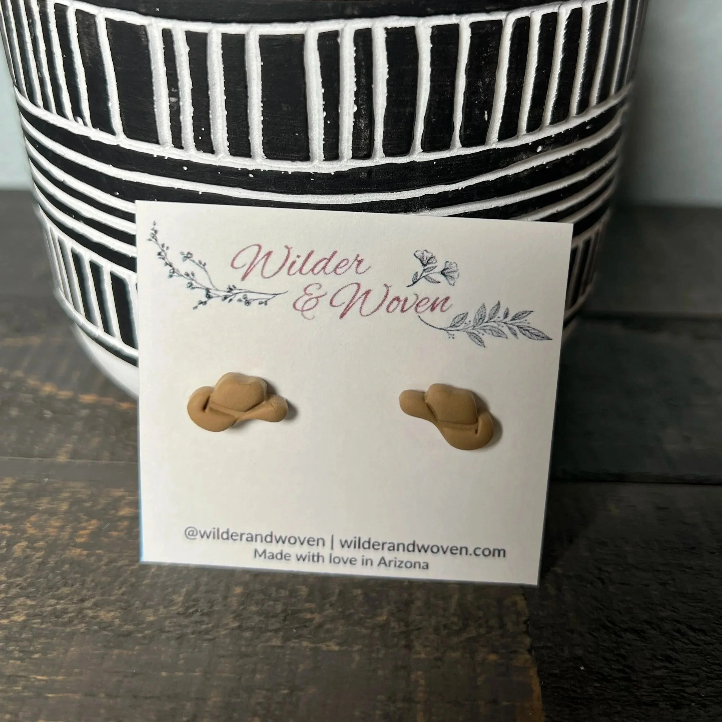 Handcrafted polymer clay cowgirl hat stud earrings in a warm sandy desert tone, displayed on a Wilder & Woven branded jewelry card.