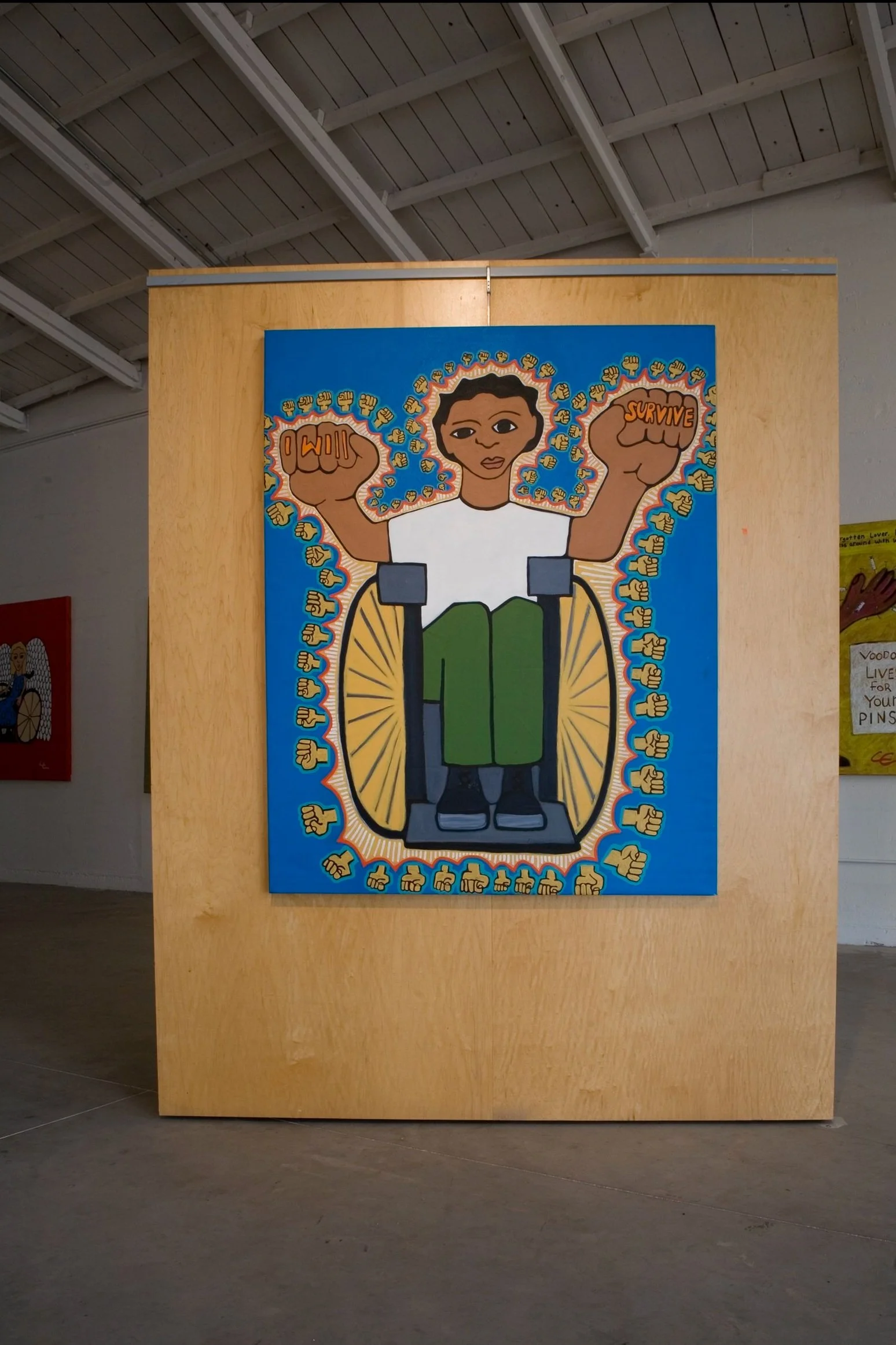 A vibrant painting of a young person in a wheelchair with their arms raised in a fist pump gesture. The person has short dark hair and is dressed in a white shirt and green pants. The background features a blue backdrop with numerous yellow fists, some with the word 'Survive' written on one. The artwork has a bold, graphic style.
