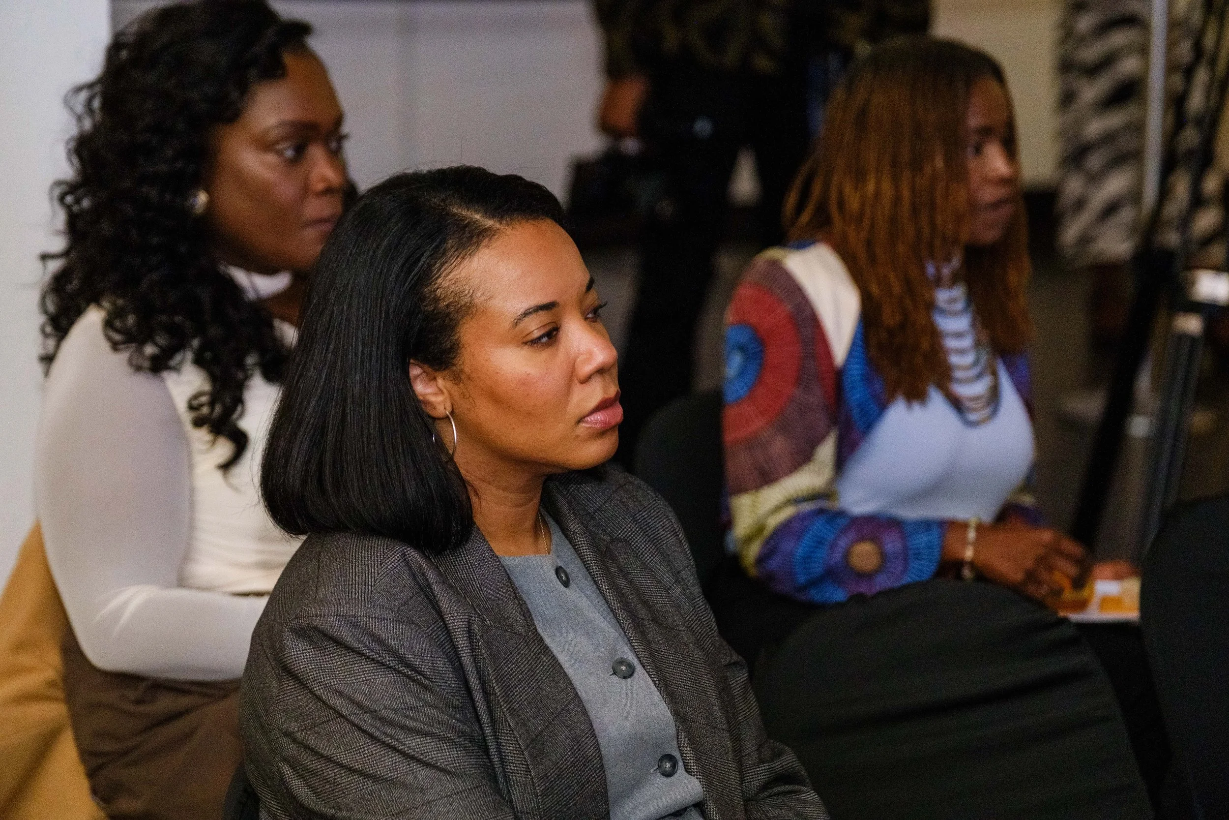 Three women sitting attentively during a meeting or seminar, with focused expressions.