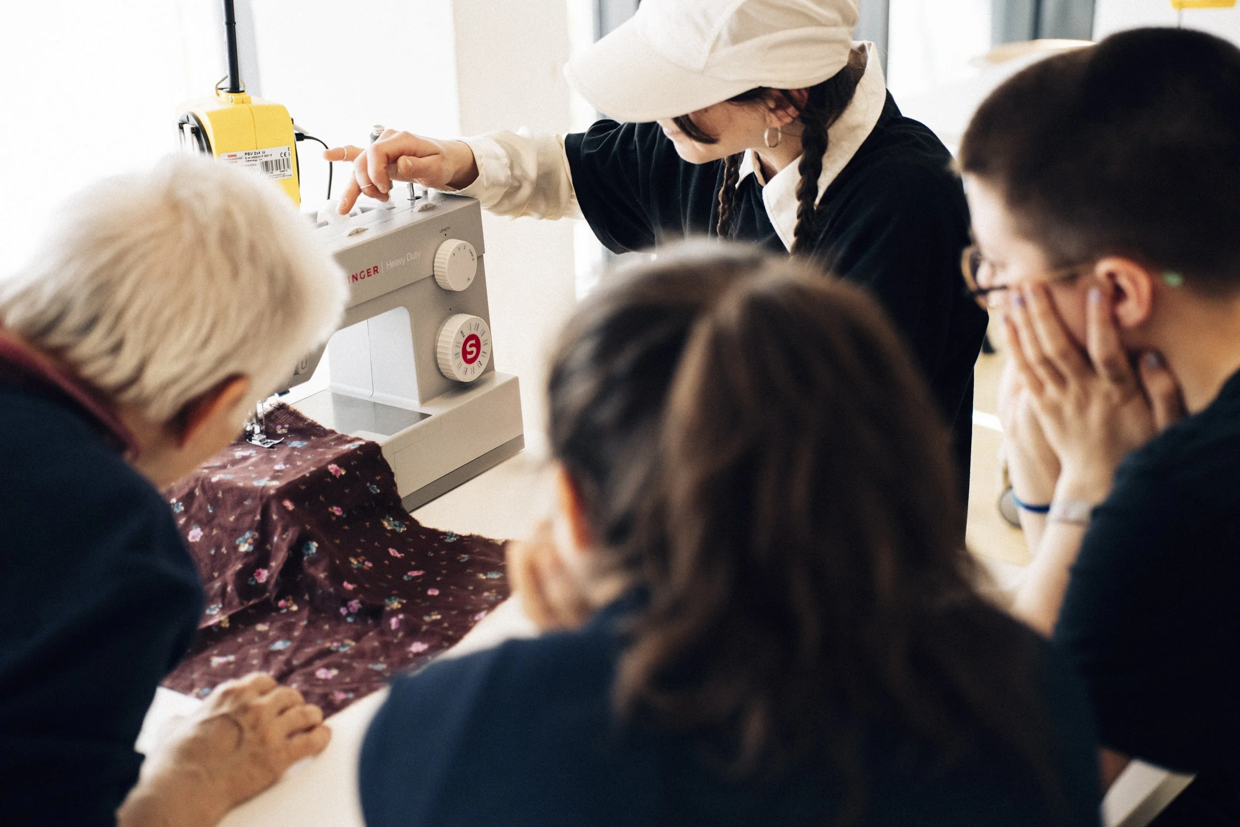 Four people gathering around a sewing machine