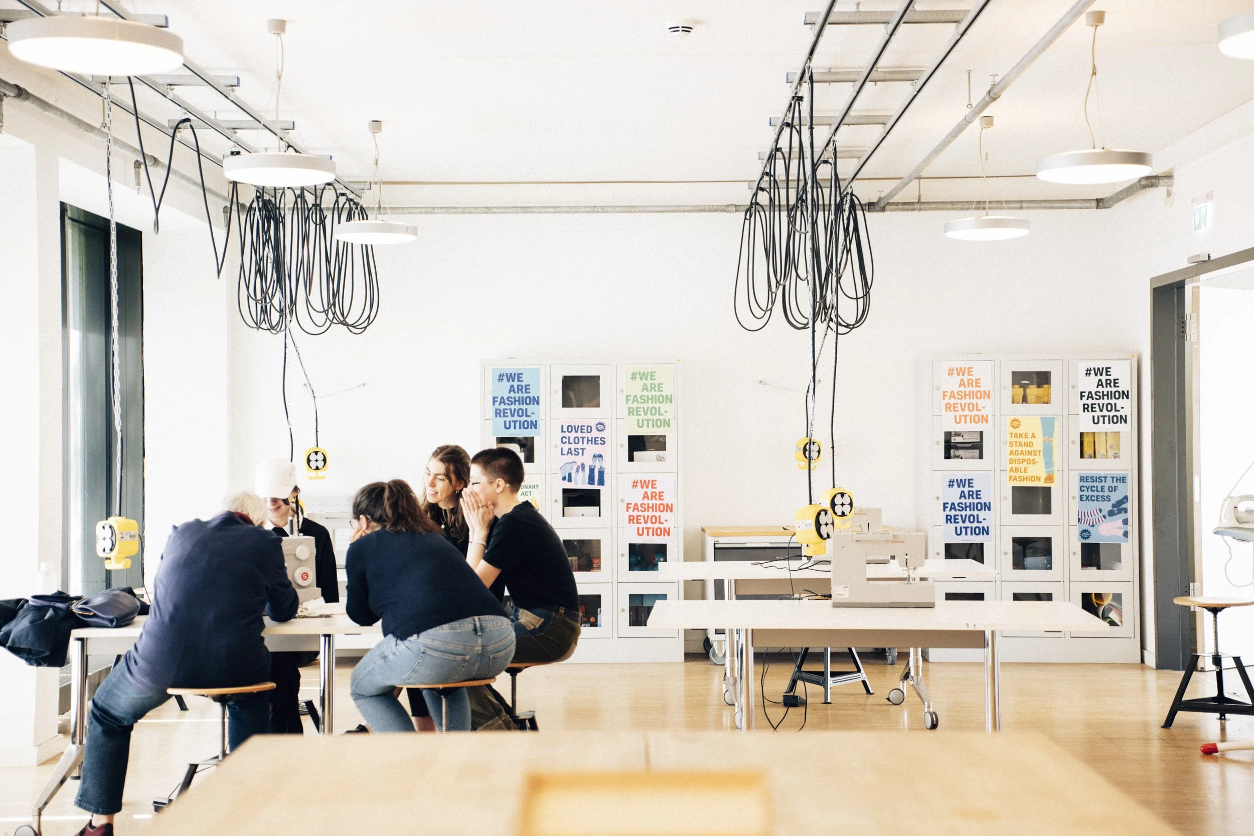 makerspace room with tables and sewing machines and 5 people sitting around one of the machines