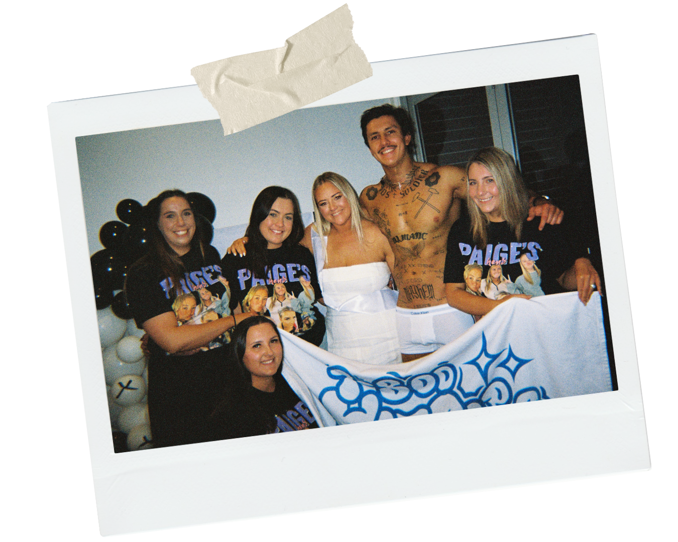 a group of women posing for a group photo with a melbourne topless waiter holding up a towel that says '1-800 hotcops'