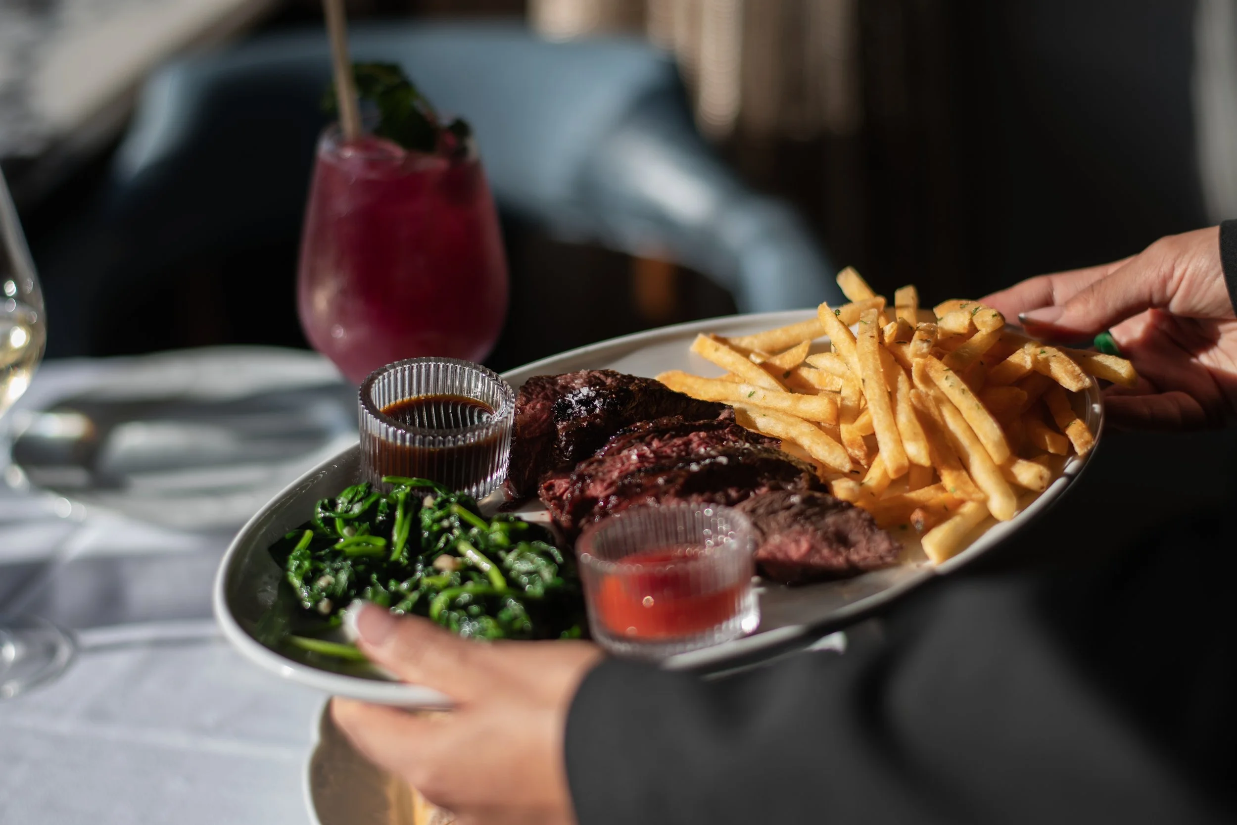 Des mains qui tiennent un plat au restaurant.