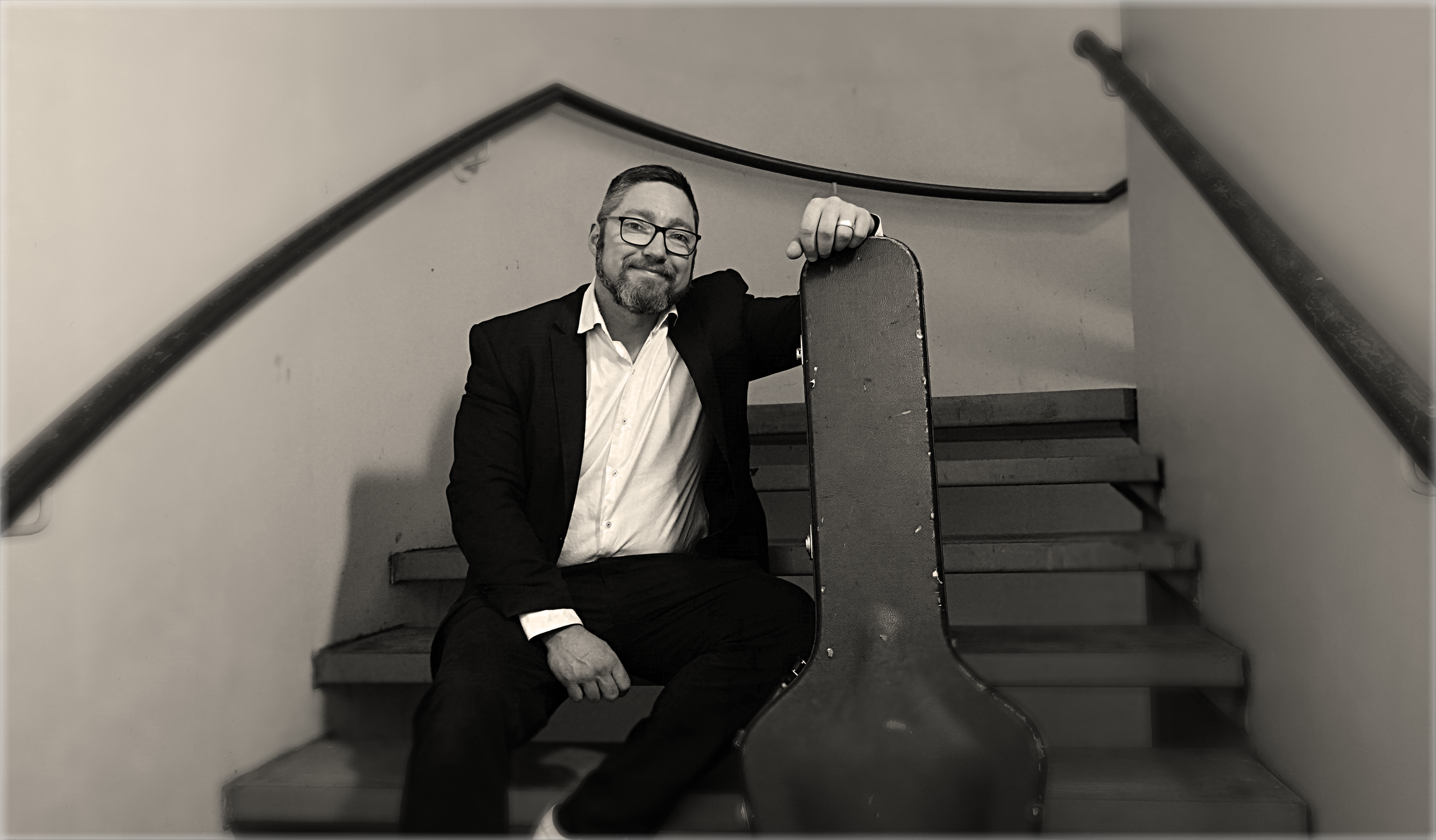 Solo adelaide musician, Jasper C Music, sits on the step of a private event, in black and white photo.