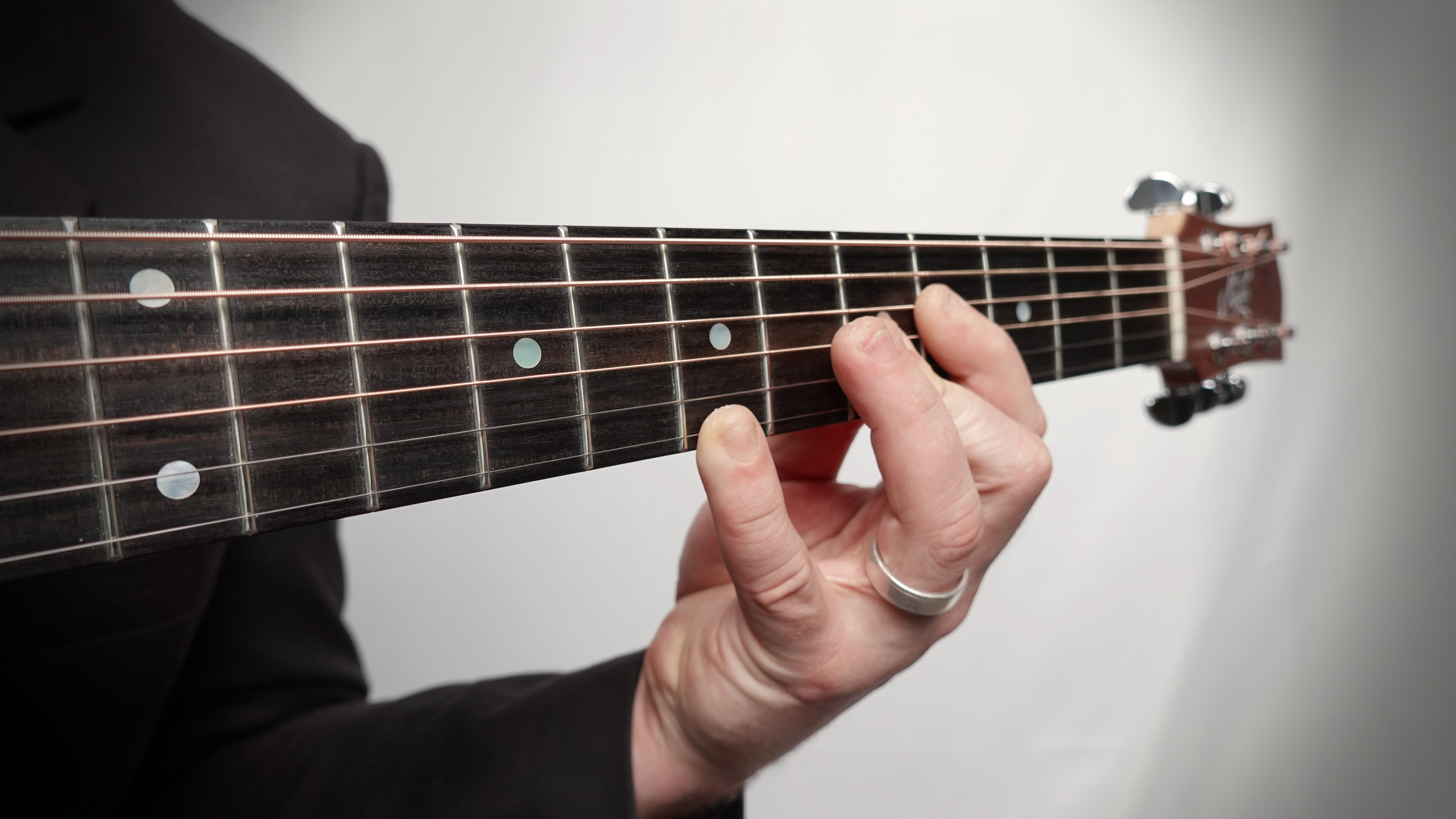 Close up image of a hand holding strings on neck of guitar