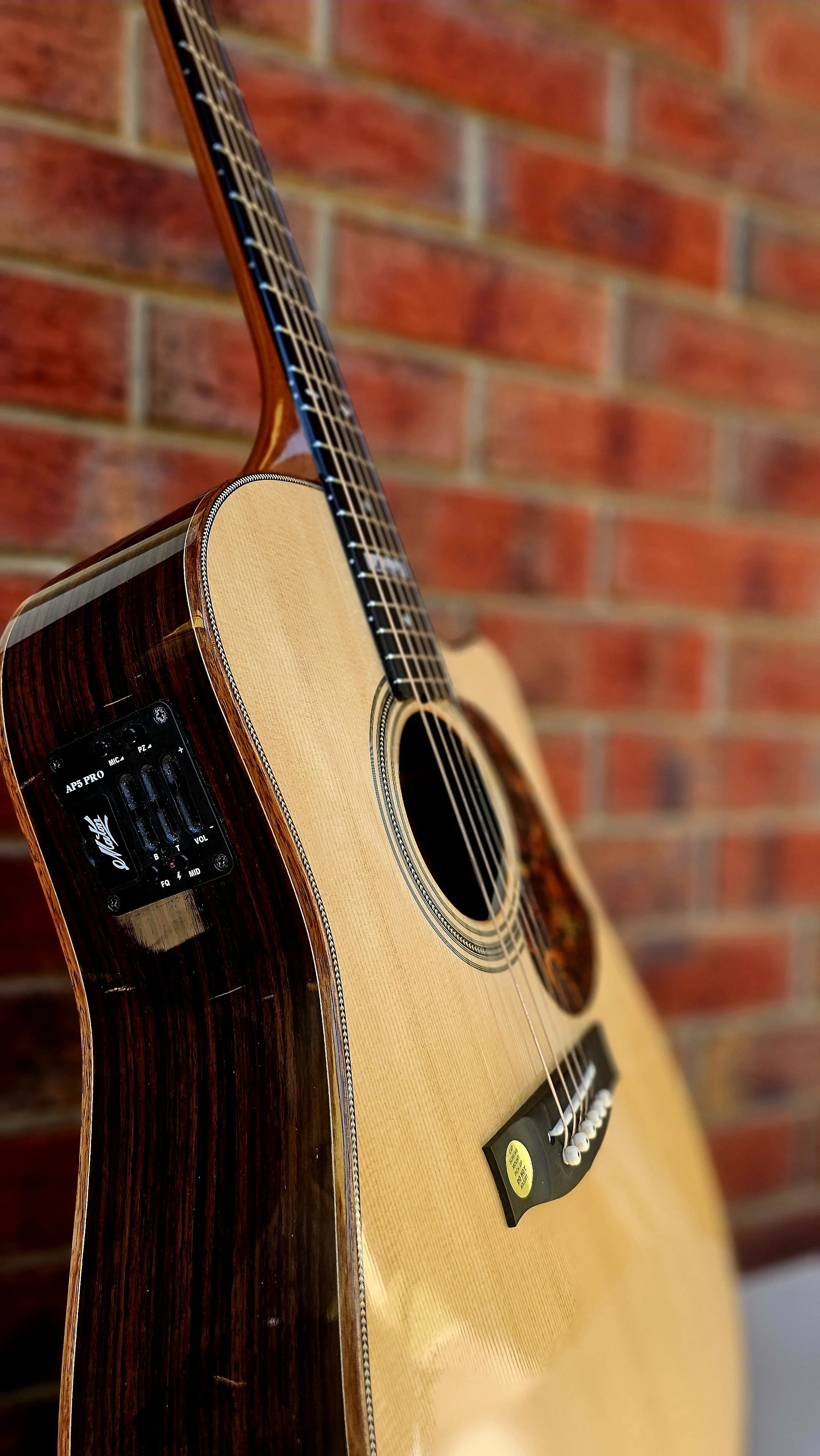 Acoustic Guitar against red brick wall