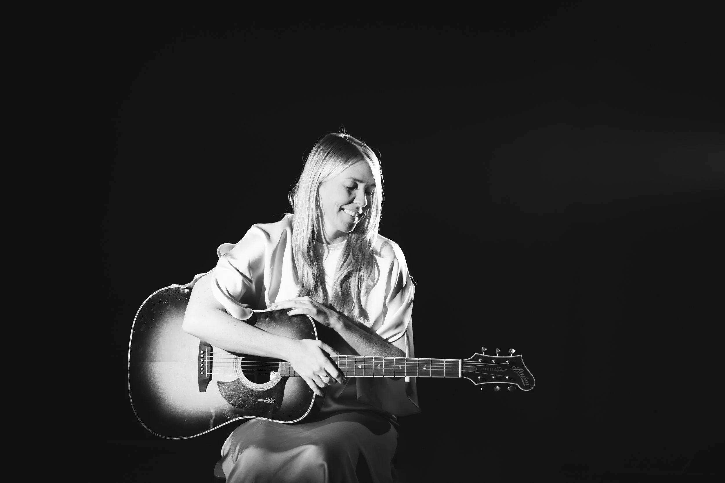 Sort-hvidt foto af en kvinde, der spiller guitar