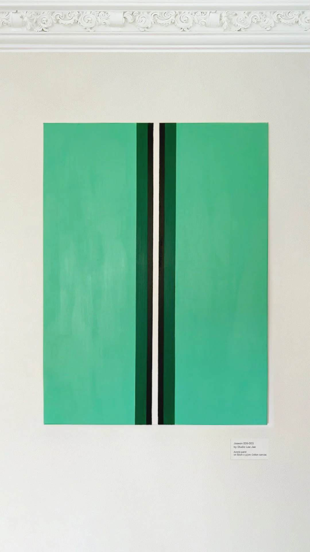 An abstract painting on a canvas featuring a vertical black and white striped design against a large green background, displayed on a white wall with ornate crown molding above.