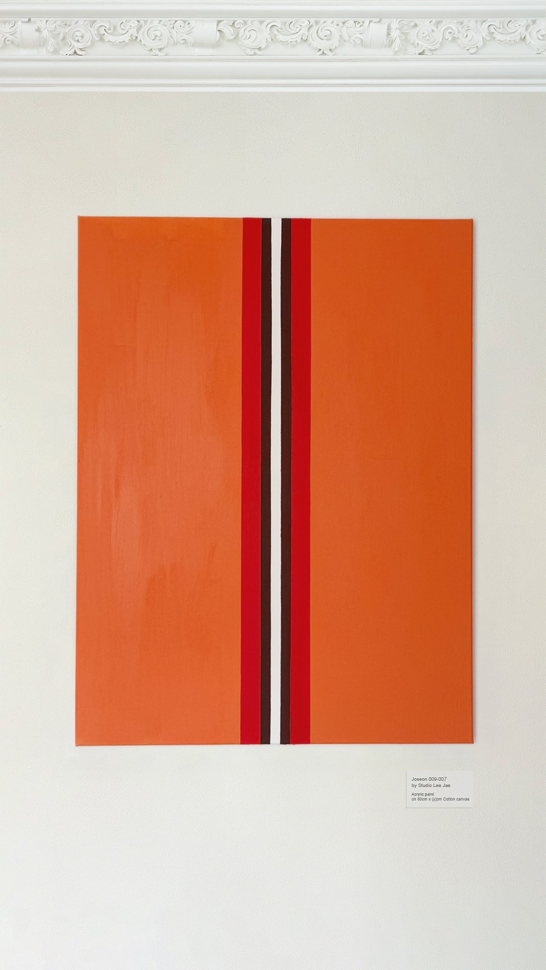 An abstract painting with vertical stripes in orange, red, black, and white, displayed on a white gallery wall with decorative molding at the top.