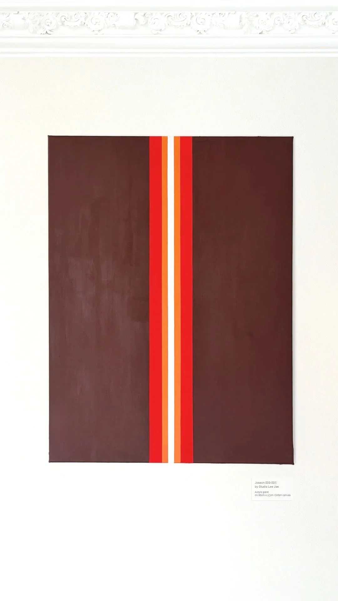 A modern acrylic painting on canvas featuring a symmetrical geometric design with a dark red background, a vertical central stripe bordered by thin orange and white lines.