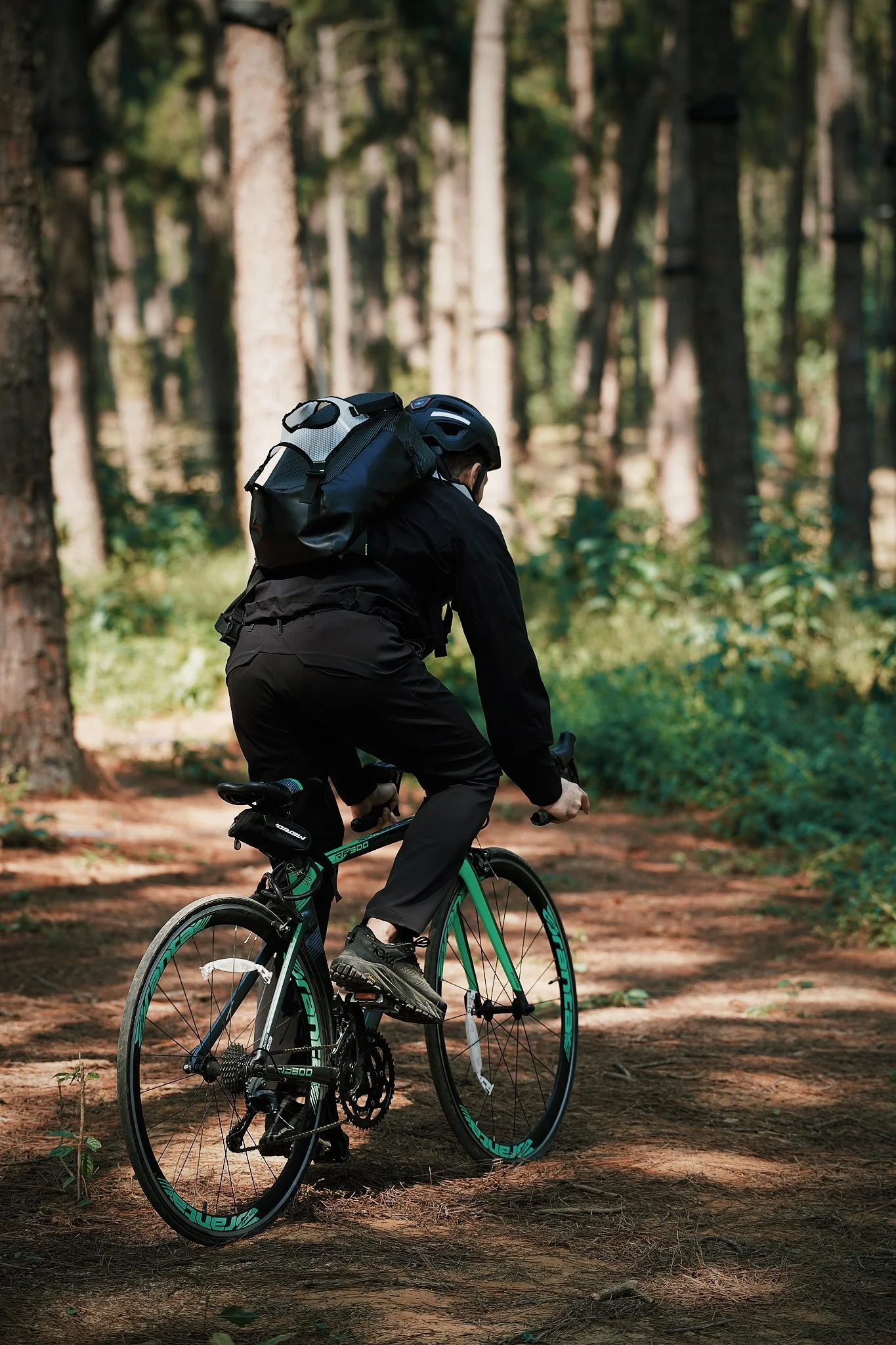 A person riding a mountain bike on a dirt trail in a forest.