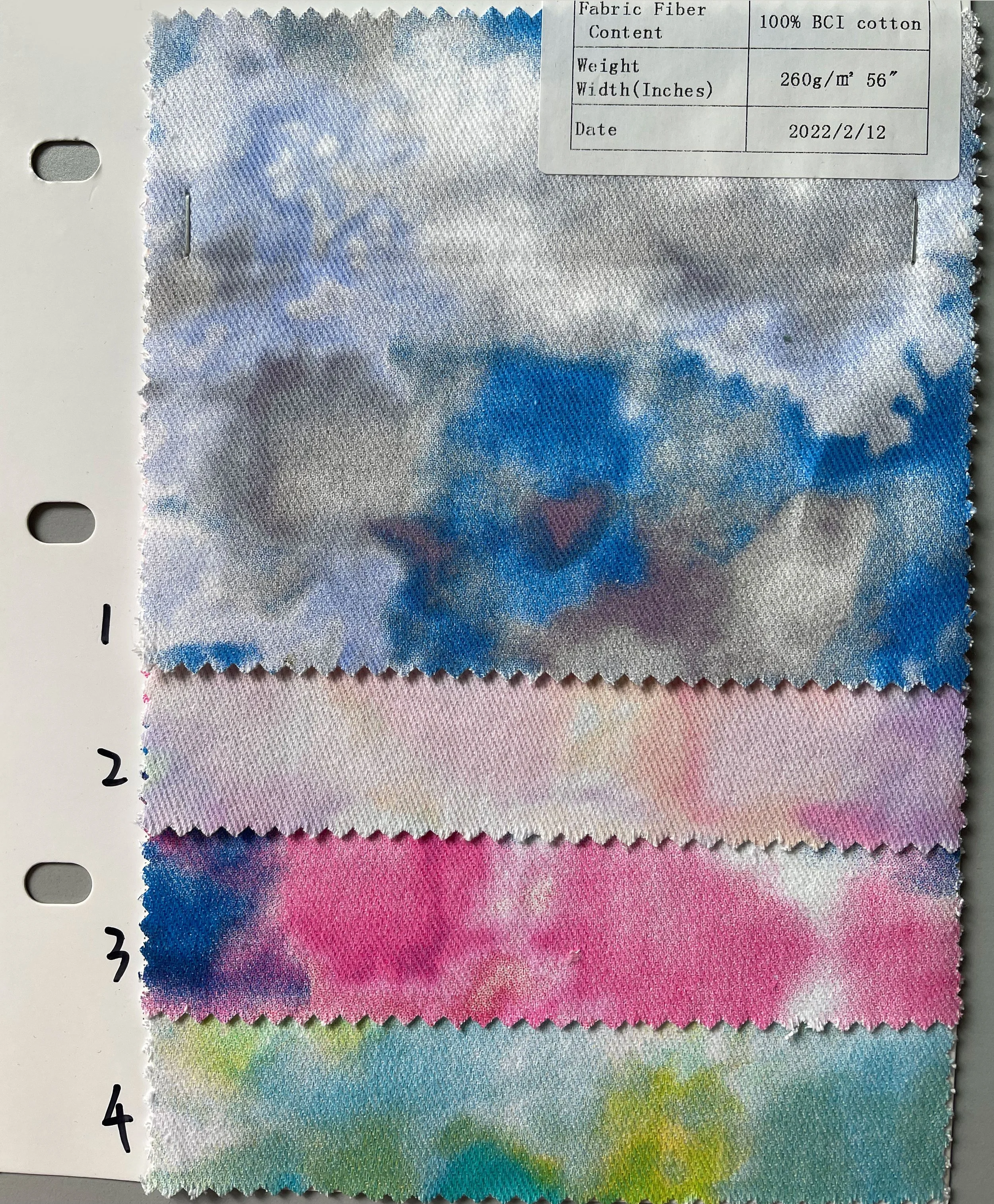 Four fabric swatches with tie-dye patterns in shades of blue, pink, and multicolor, arranged vertically on a white background, with a label in the top right corner displaying fabric details and date.