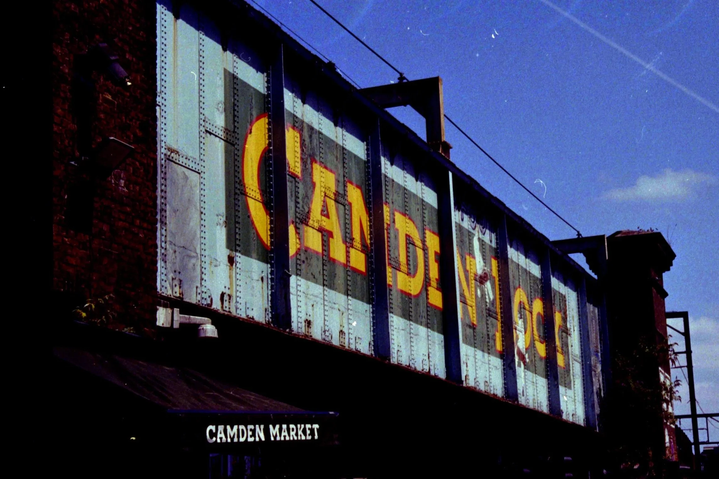 A vintage billboard advertising Camden Market with a dark blue sky in the background.