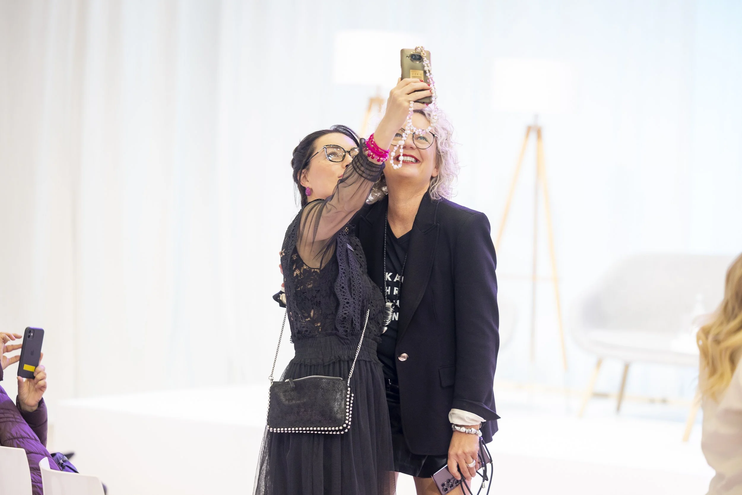 Zwei Frauen nehmen gemeinsam ein Selfie auf der Top Hair Messe für Friseure in Düsseldorf auf, eine lacht.